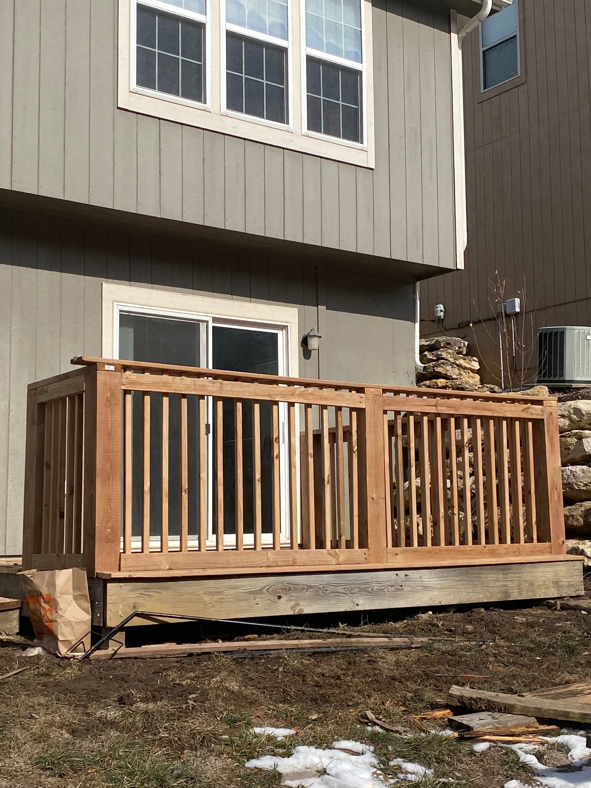A wooden deck is sitting in front of a house.