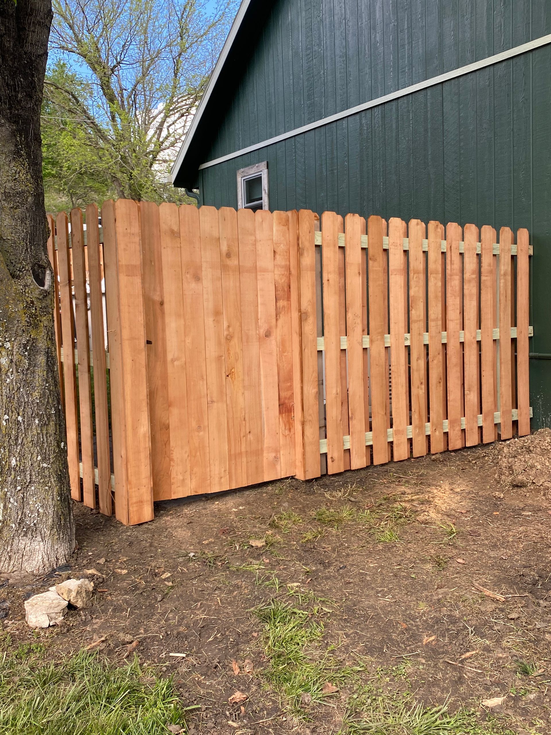 A wooden fence is sitting in front of a green building.