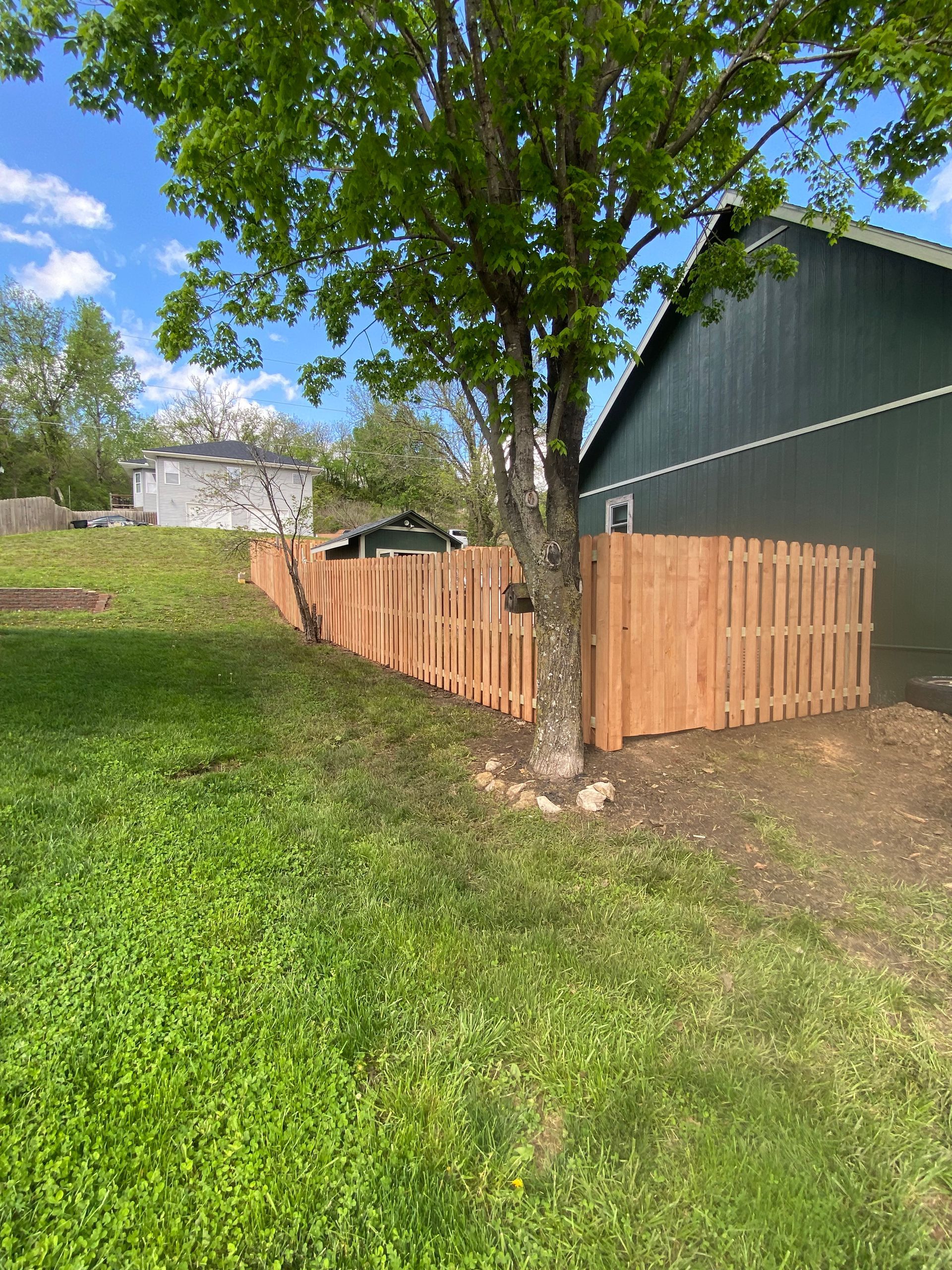 A wooden fence is in the backyard of a house.