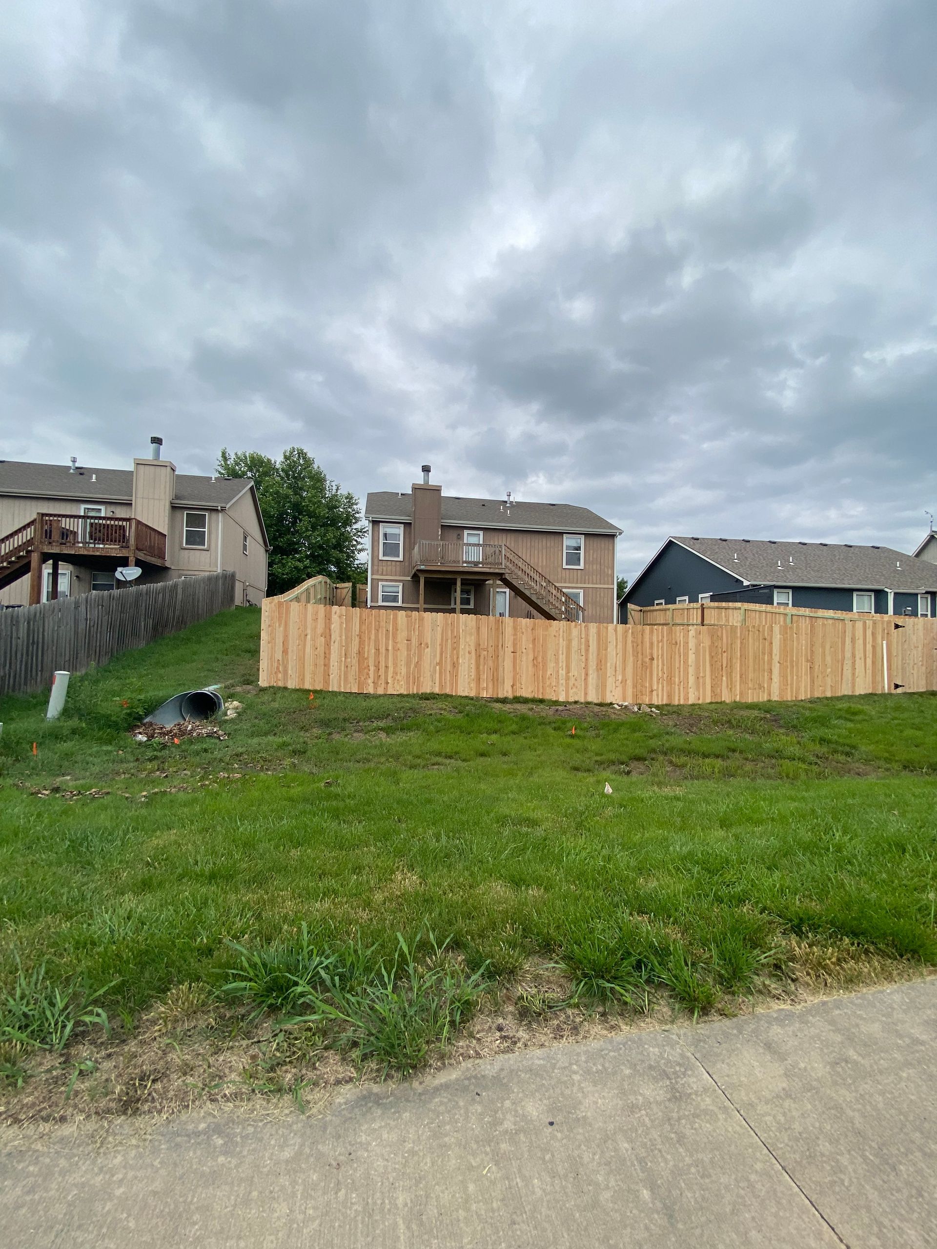 There is a wooden fence in the middle of a grassy field.