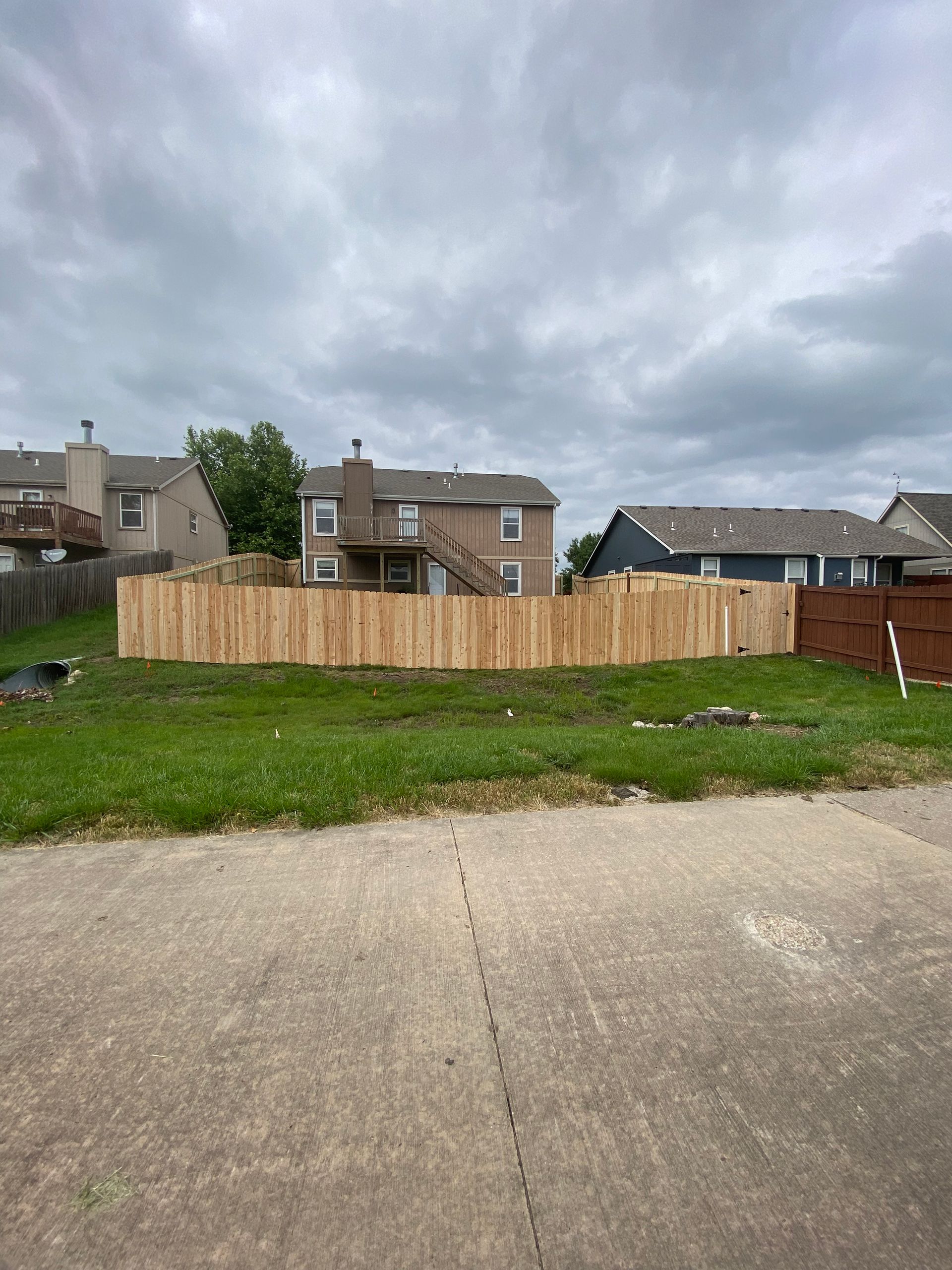 There is a wooden fence in the middle of a grassy field.