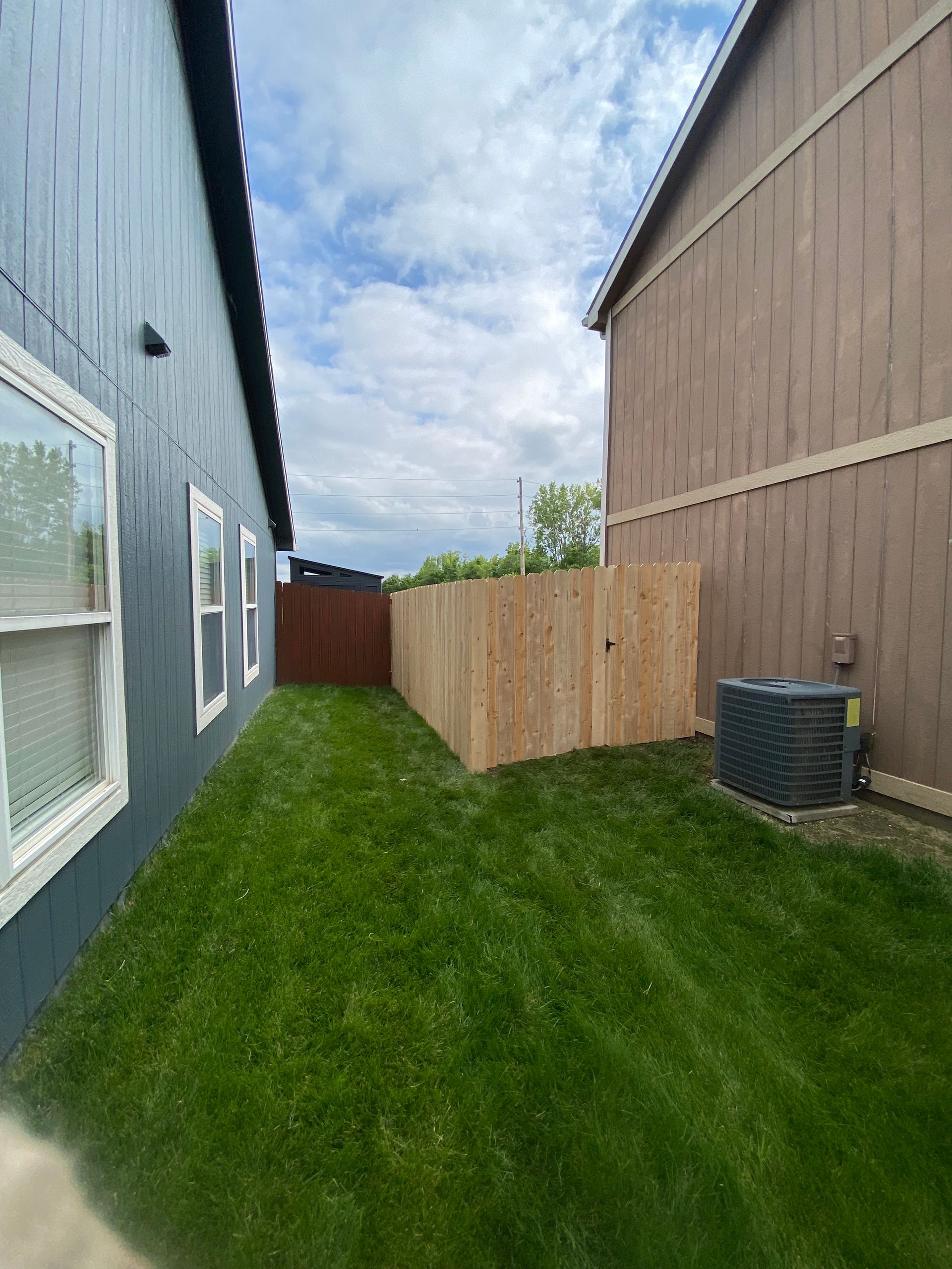 There is a wooden fence in the backyard between two houses.