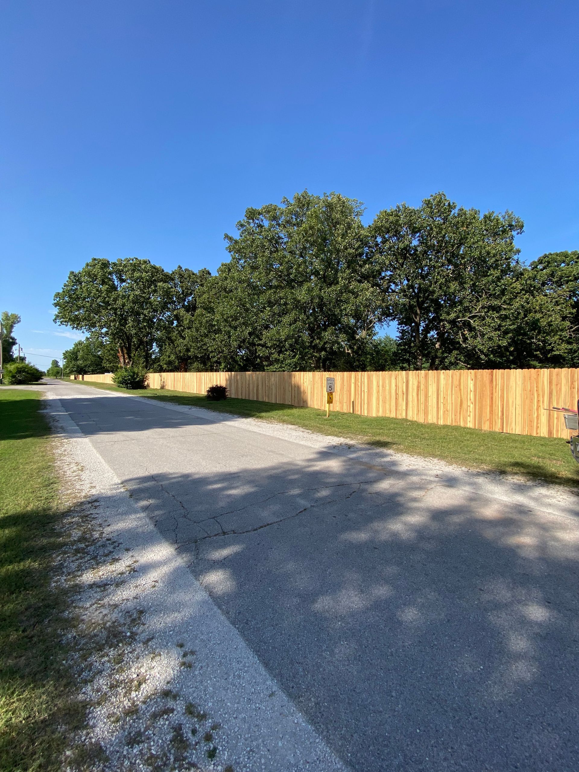 A wooden fence along the side of a gravel road.