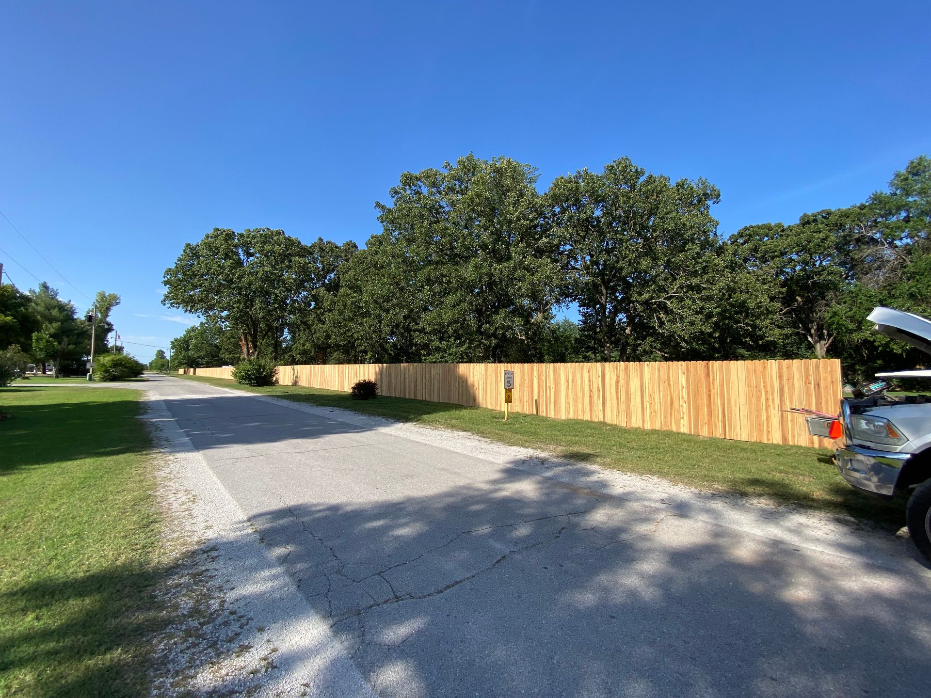 A wooden fence is along the side of a dirt road.