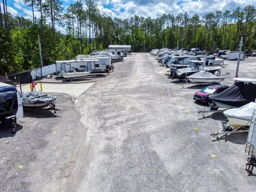 Boats stored indoors under a wooden ceiling; various sizes and covered with blue tarps.