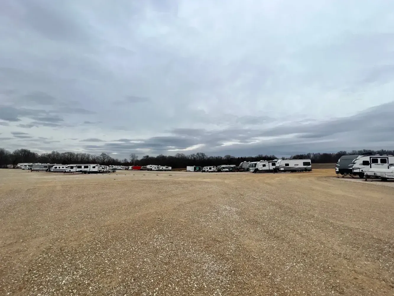 Boats and RVs parked indoors in a well-lit facility with a concrete floor.