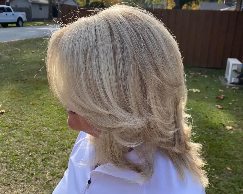 A woman with blonde hair is wearing a white nike shirt.