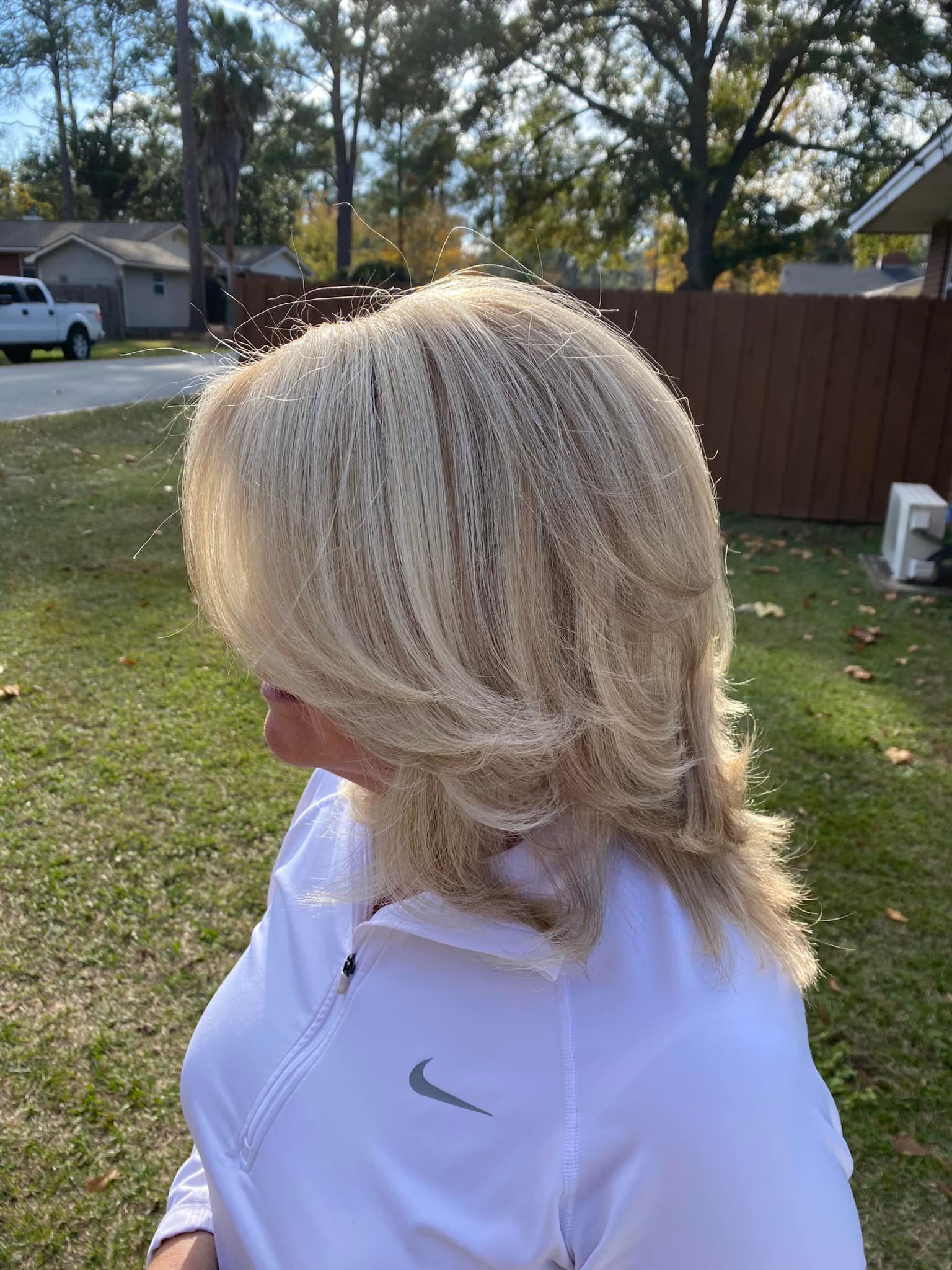A woman with blonde hair is wearing a white nike shirt.