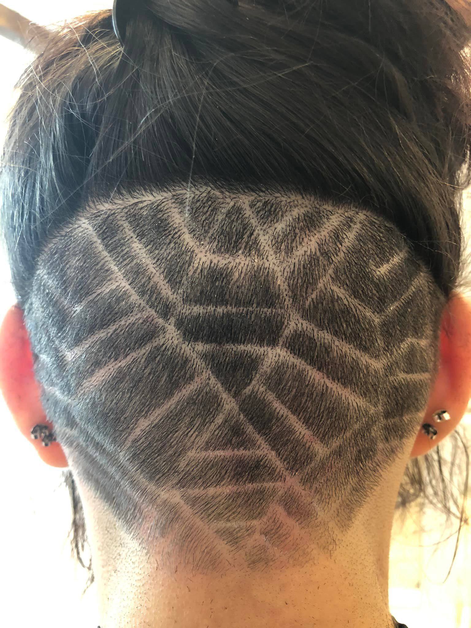 The back of a woman 's head with a shaved design on it.