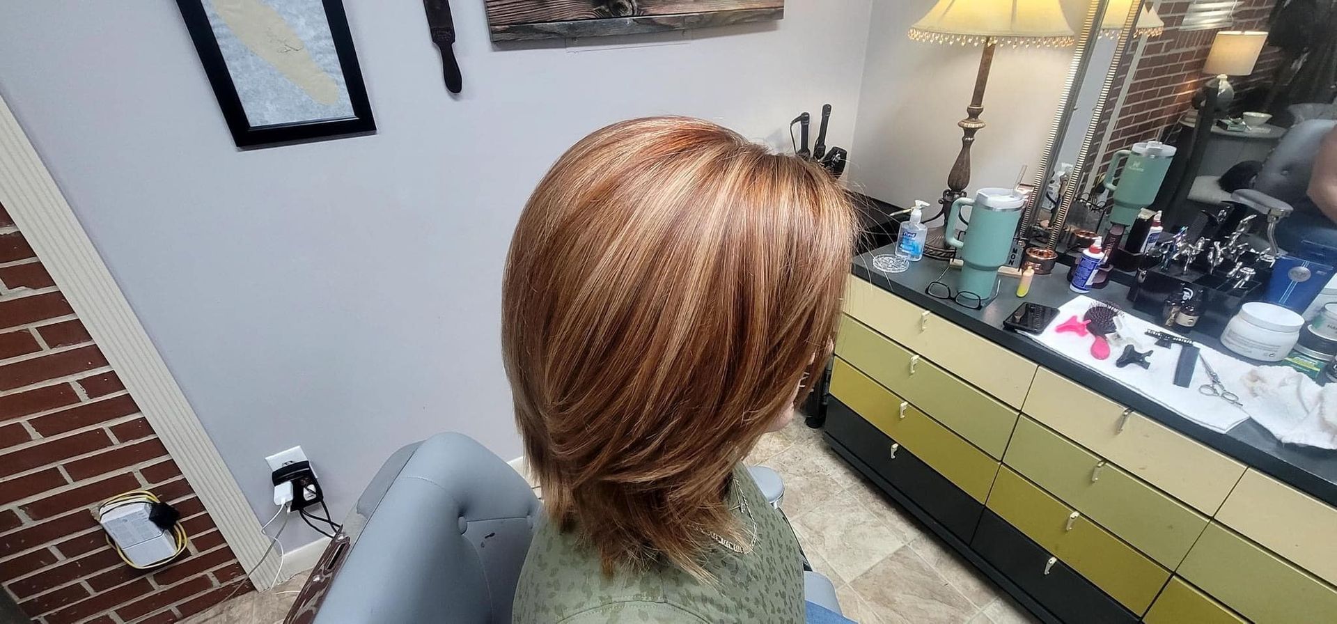 A woman is sitting in a chair in front of a mirror in a room.
