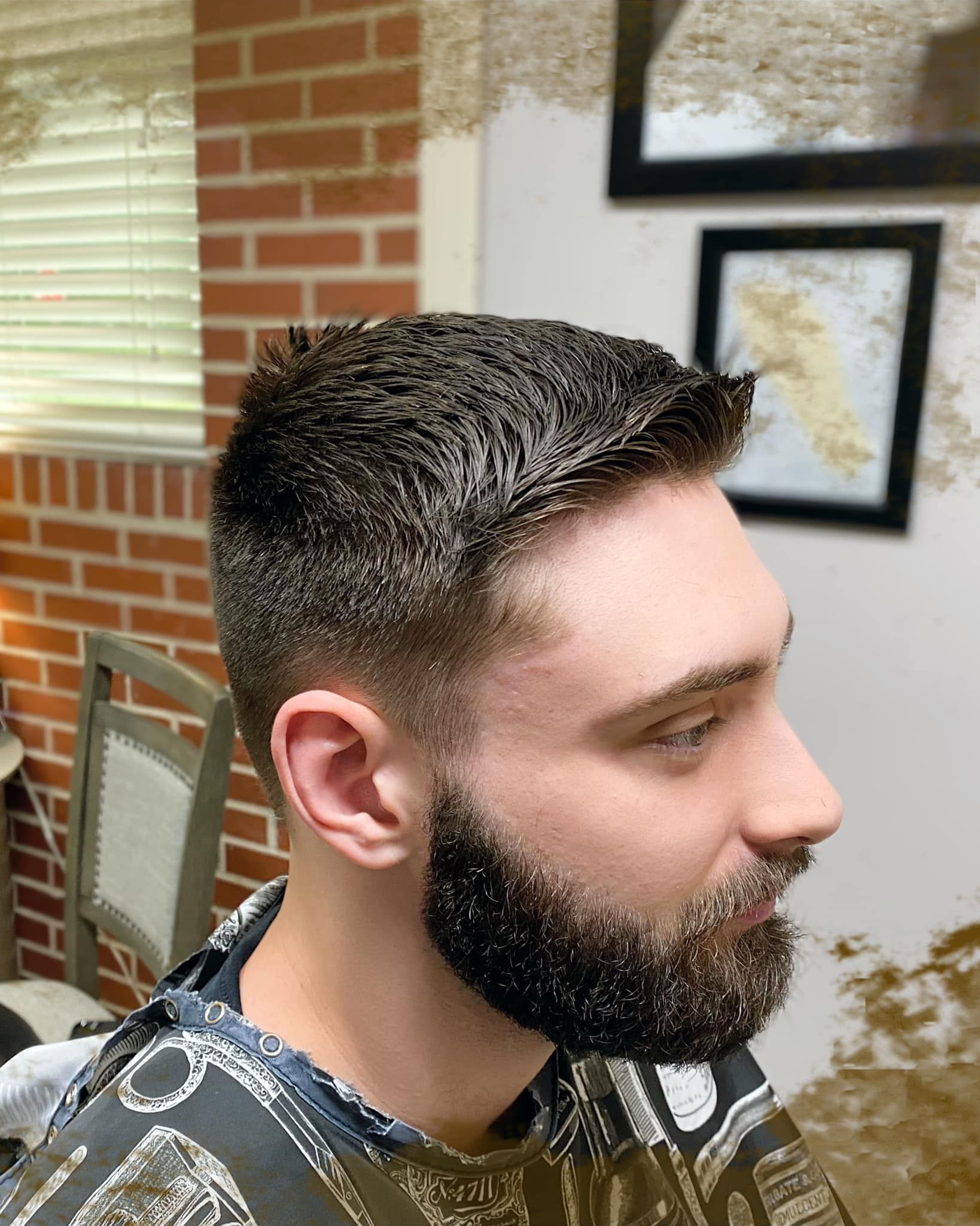 A man with a beard is getting his hair cut at a barber shop.