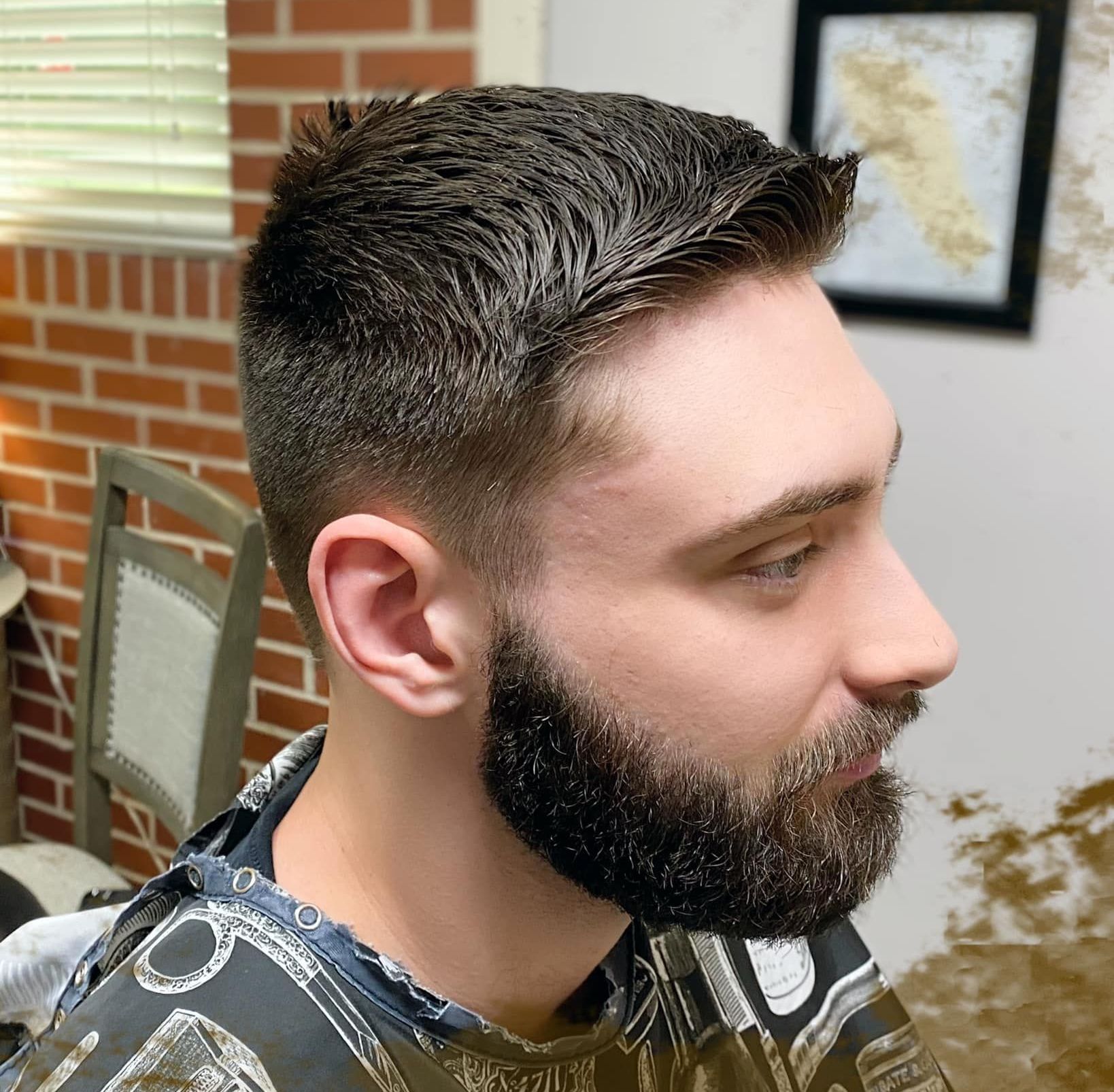 A man with a beard is getting his hair cut at a barber shop