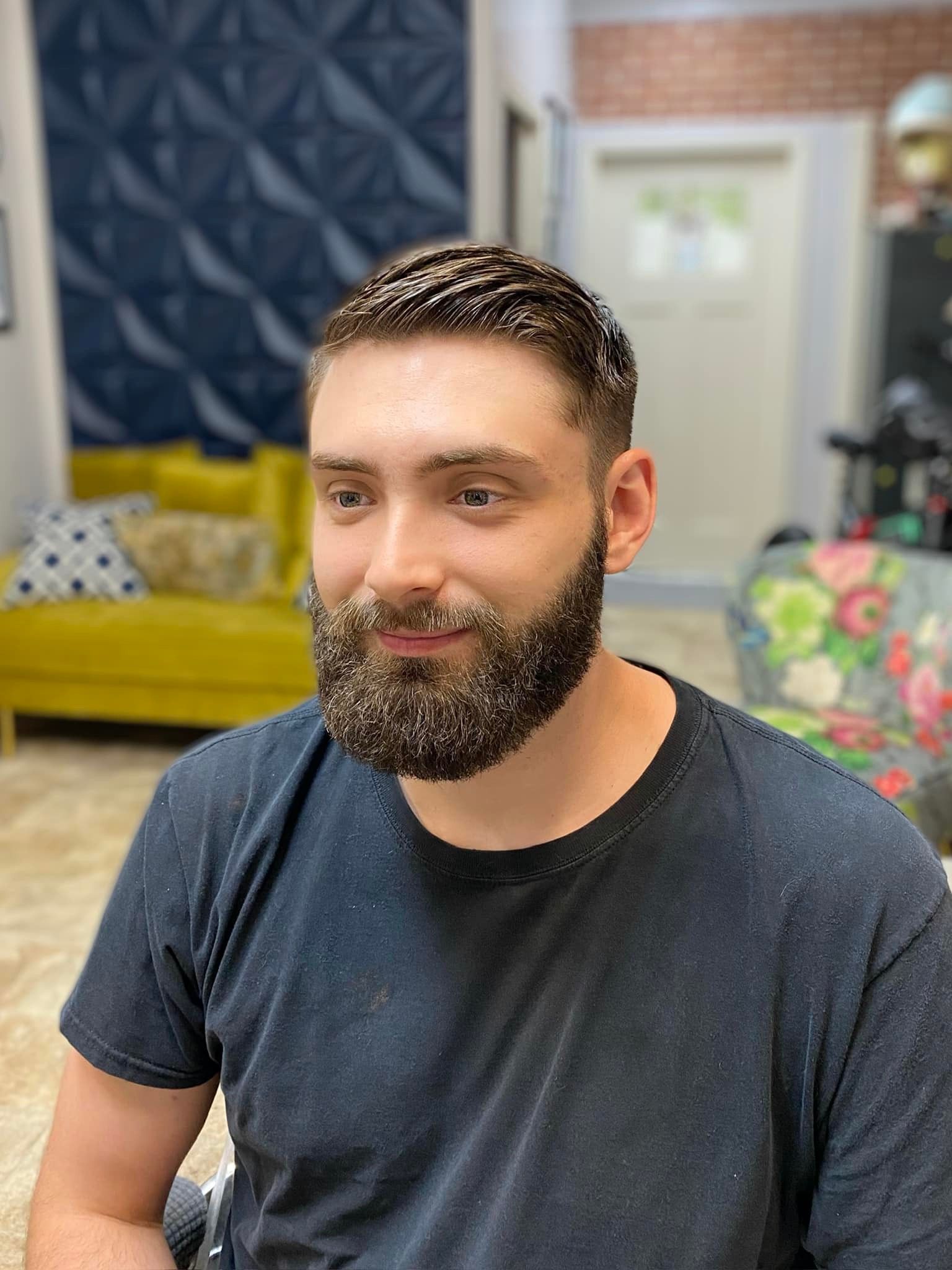 A man with a beard is wearing a black shirt and smiling.