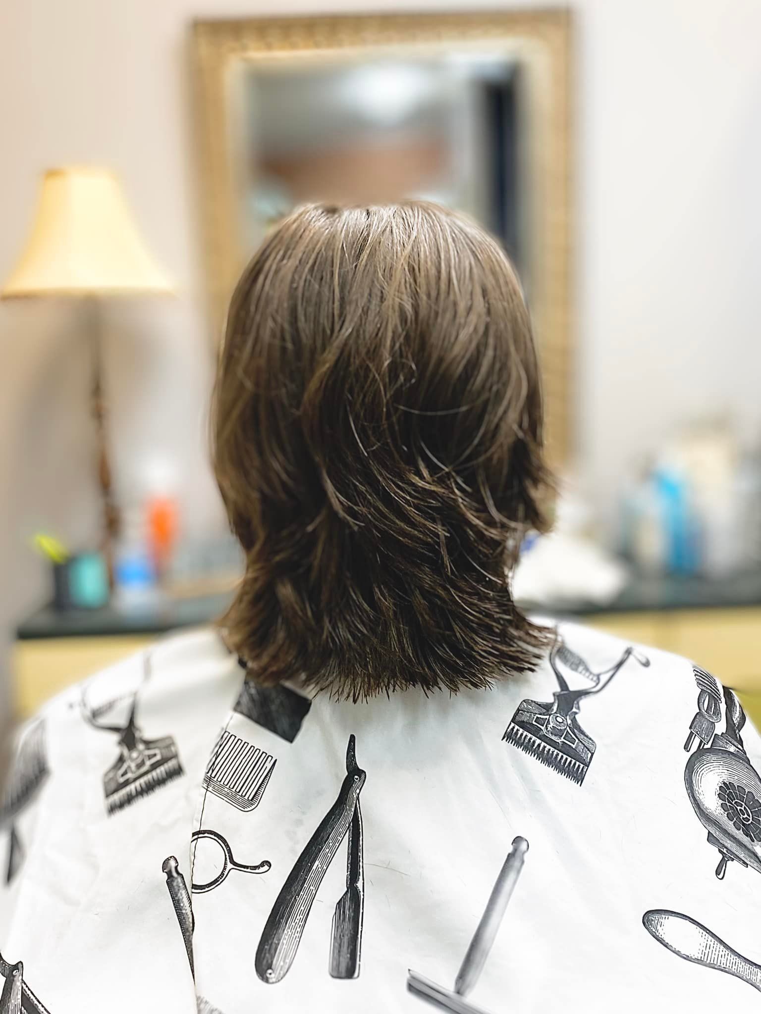 The back of a person getting their hair cut in a barber shop.