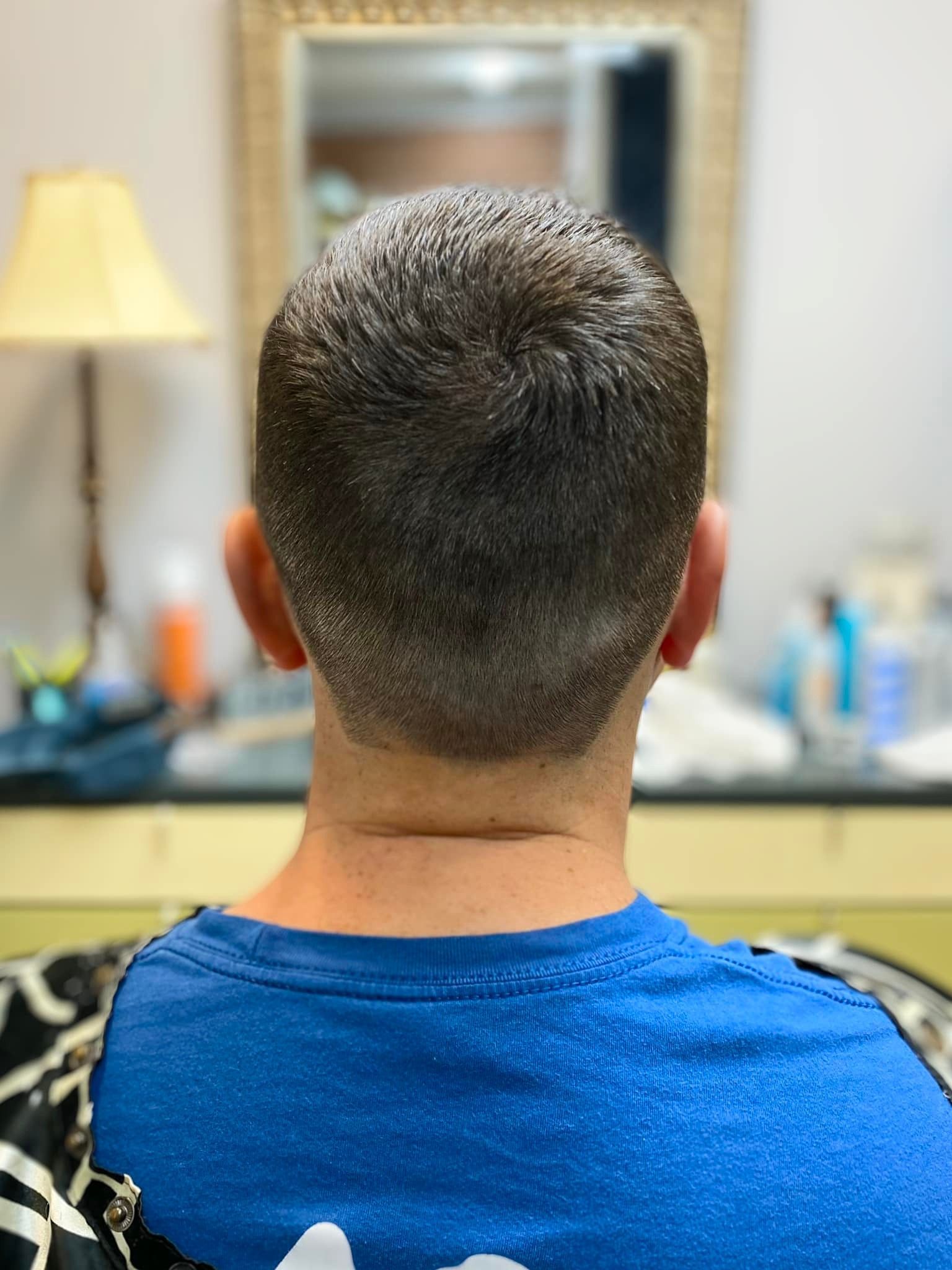 A man in a blue shirt is sitting in front of a mirror.