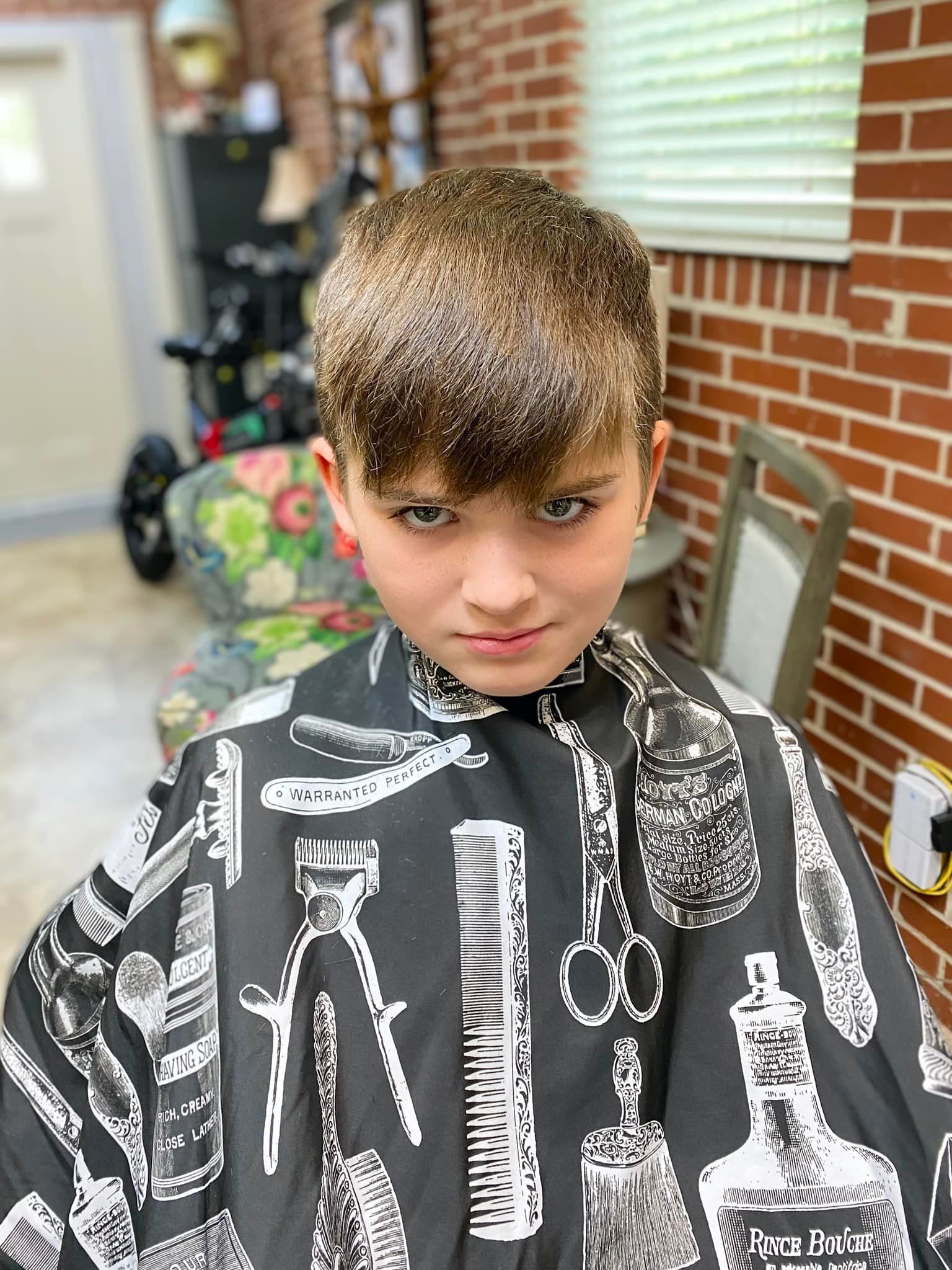 A young boy is getting his hair cut at a barber shop.