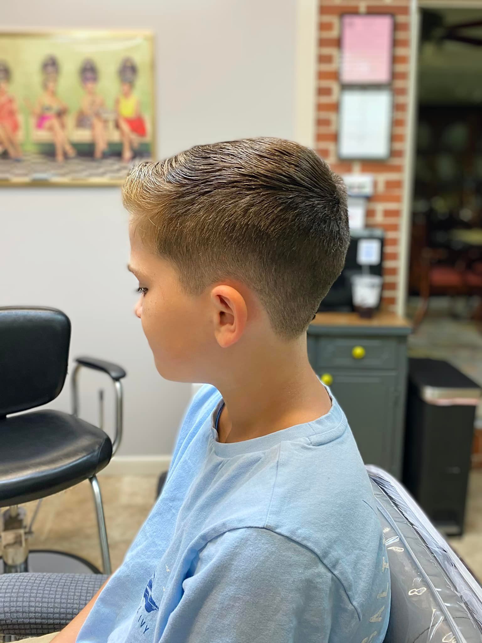 A young boy is getting his hair cut at a barber shop.