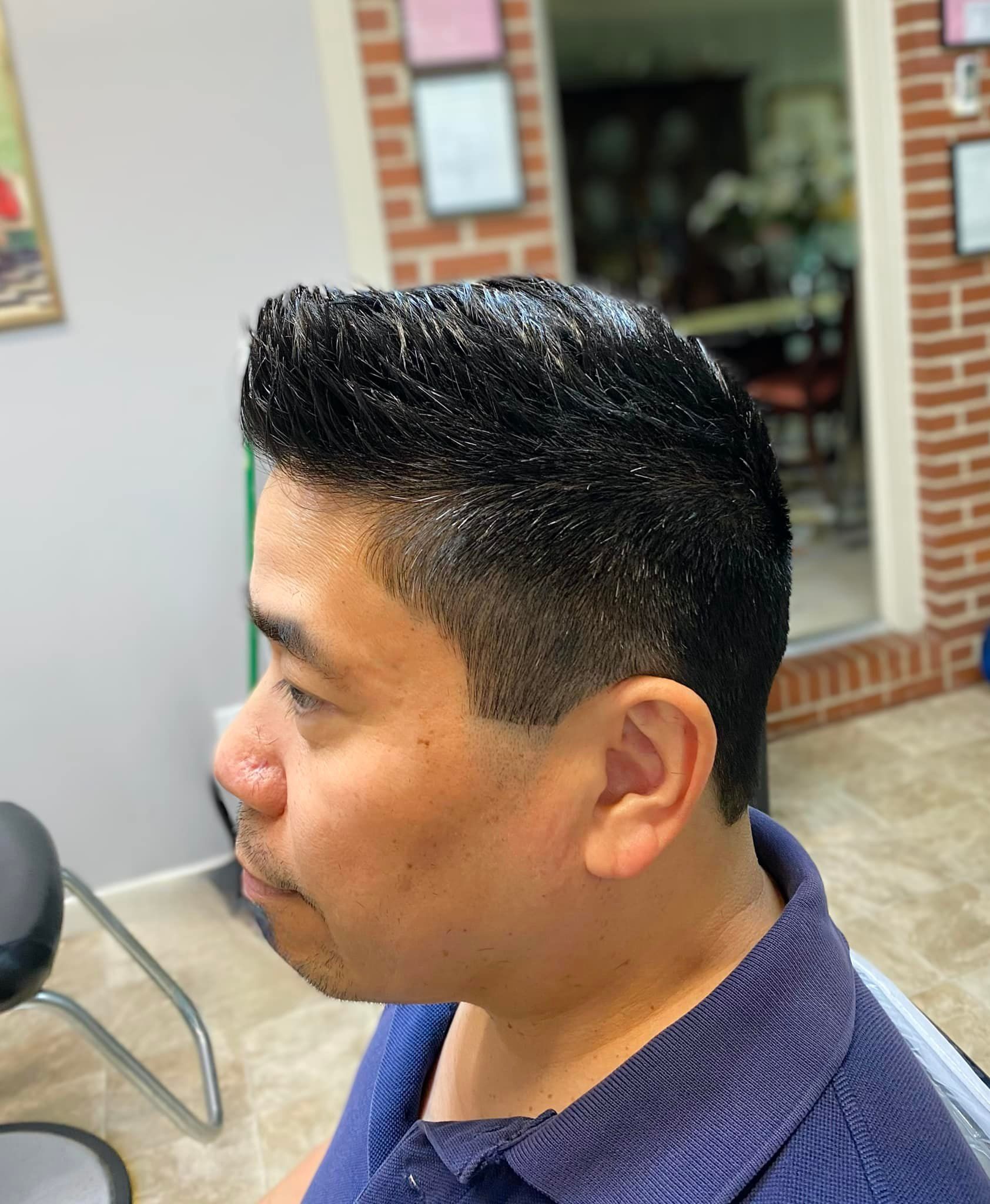 A man is getting his hair cut at a barber shop.