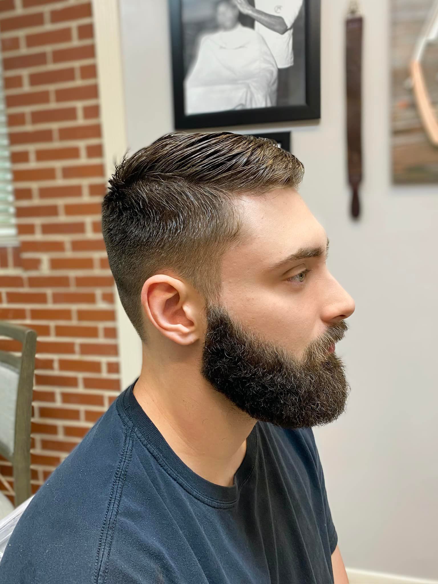 A man with a beard is getting his hair cut at a barber shop.