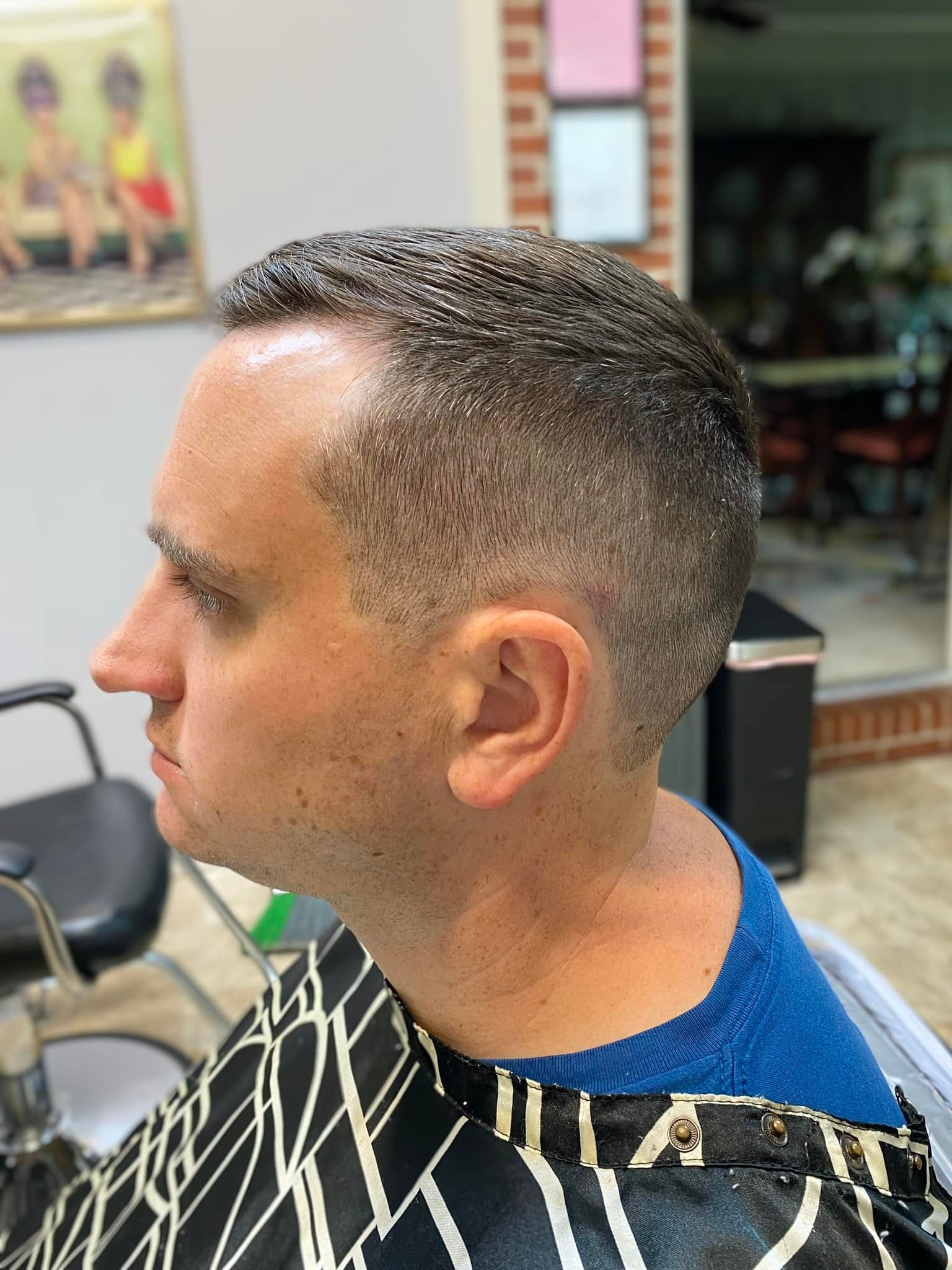 A man is getting his hair cut at a barber shop.
