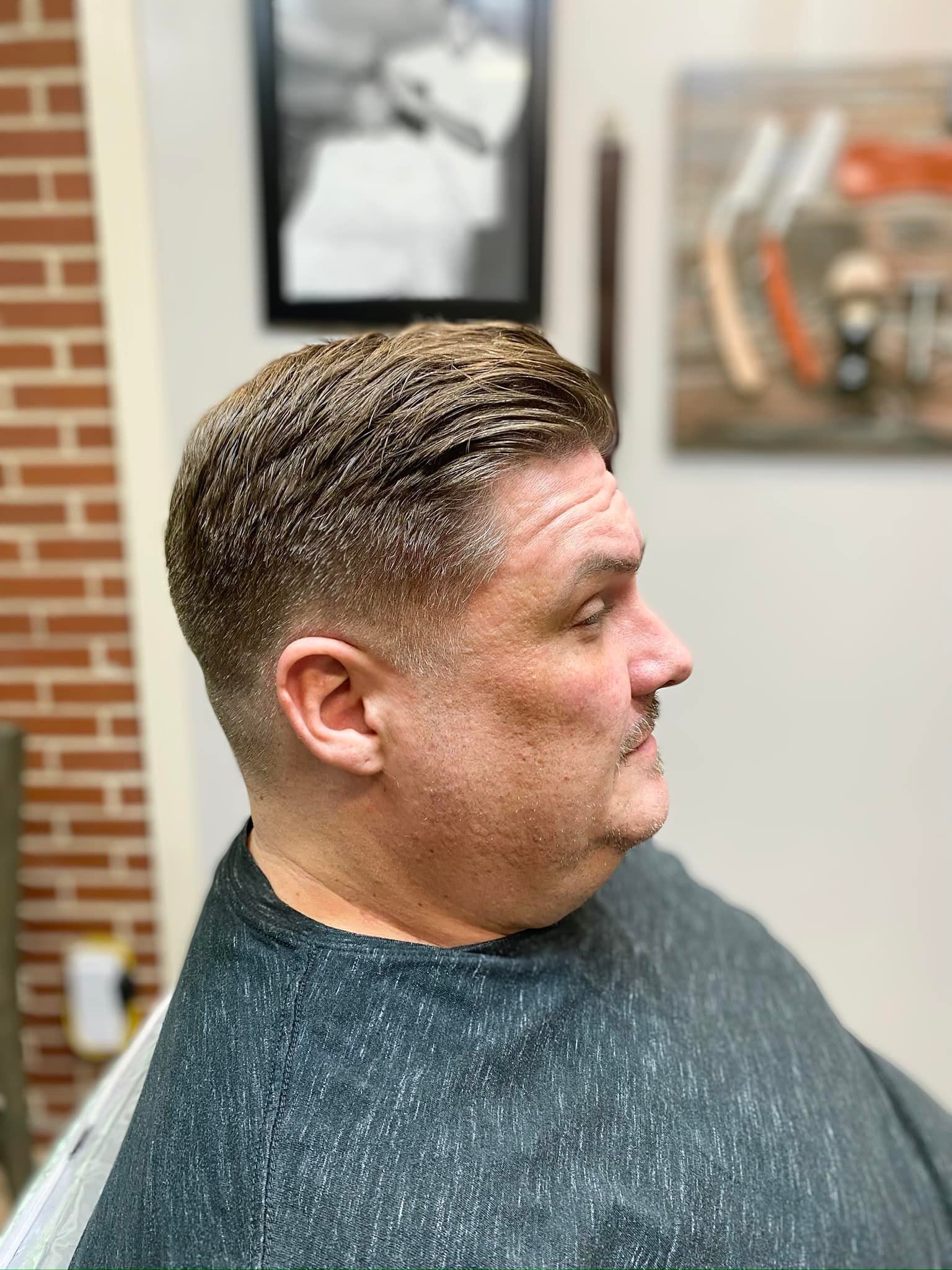 A man is getting his hair cut at a barber shop.