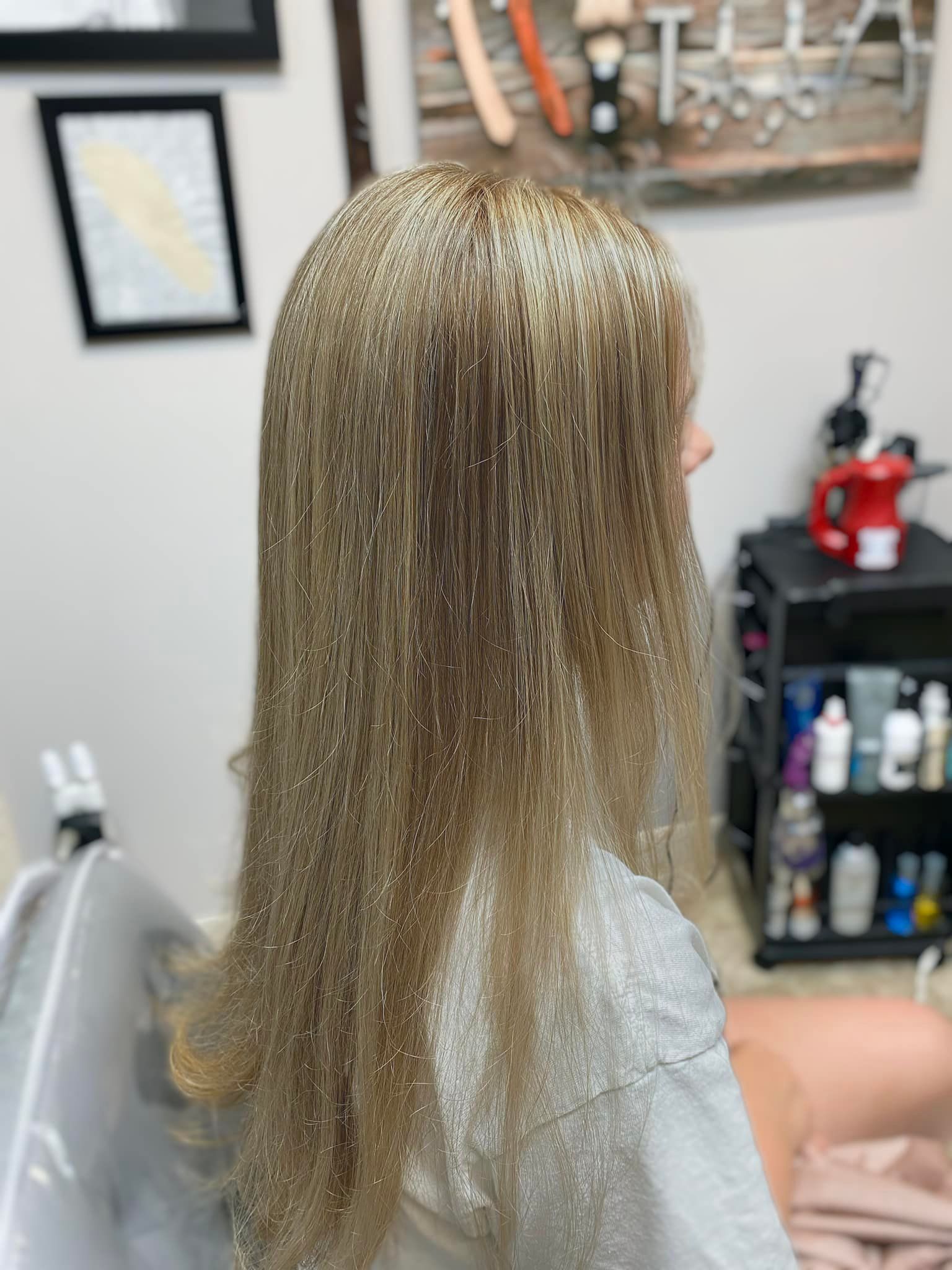 A woman with long blonde hair is sitting in a chair in a salon.