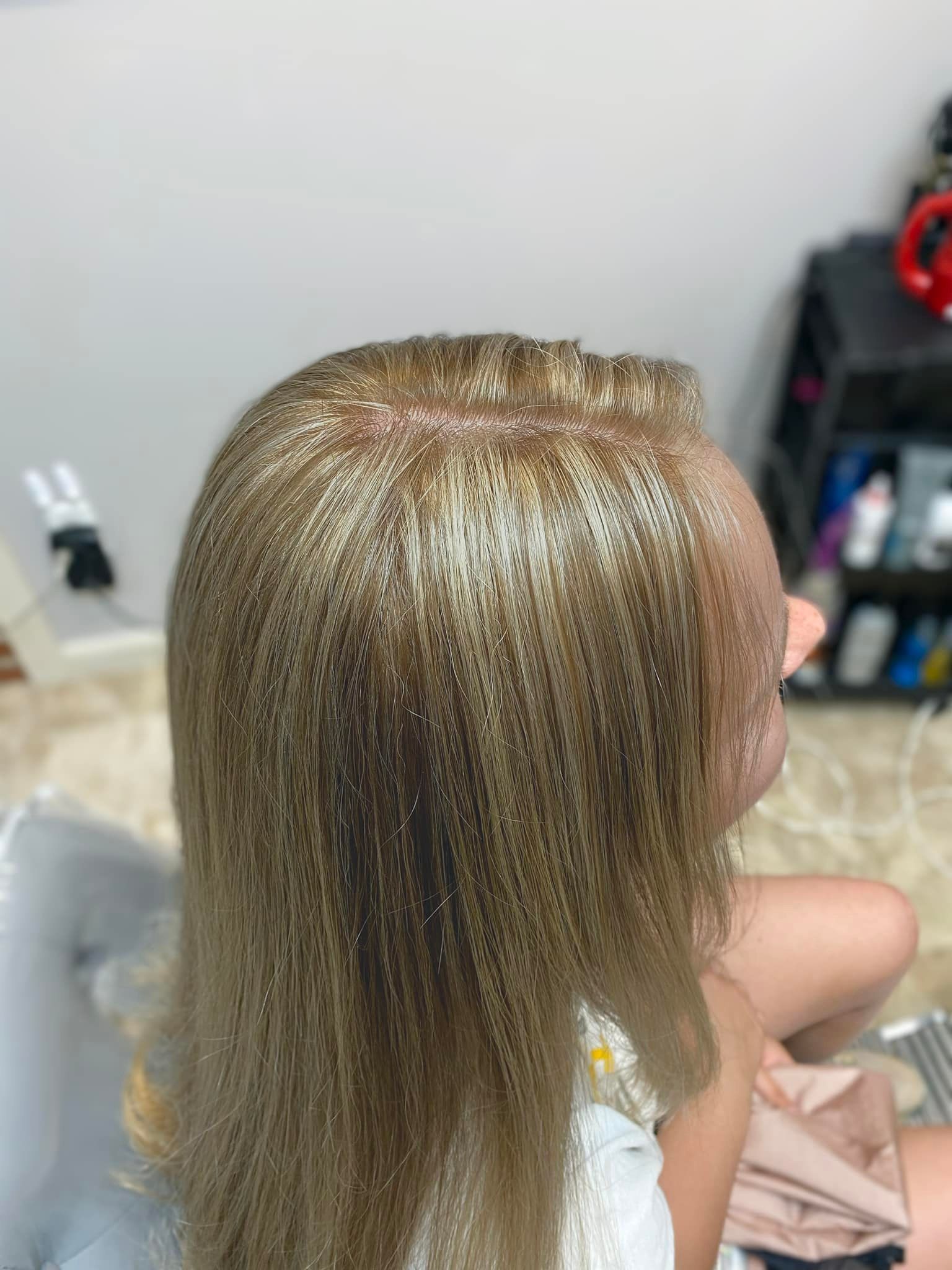 A woman with blonde hair is sitting in a chair in a room.