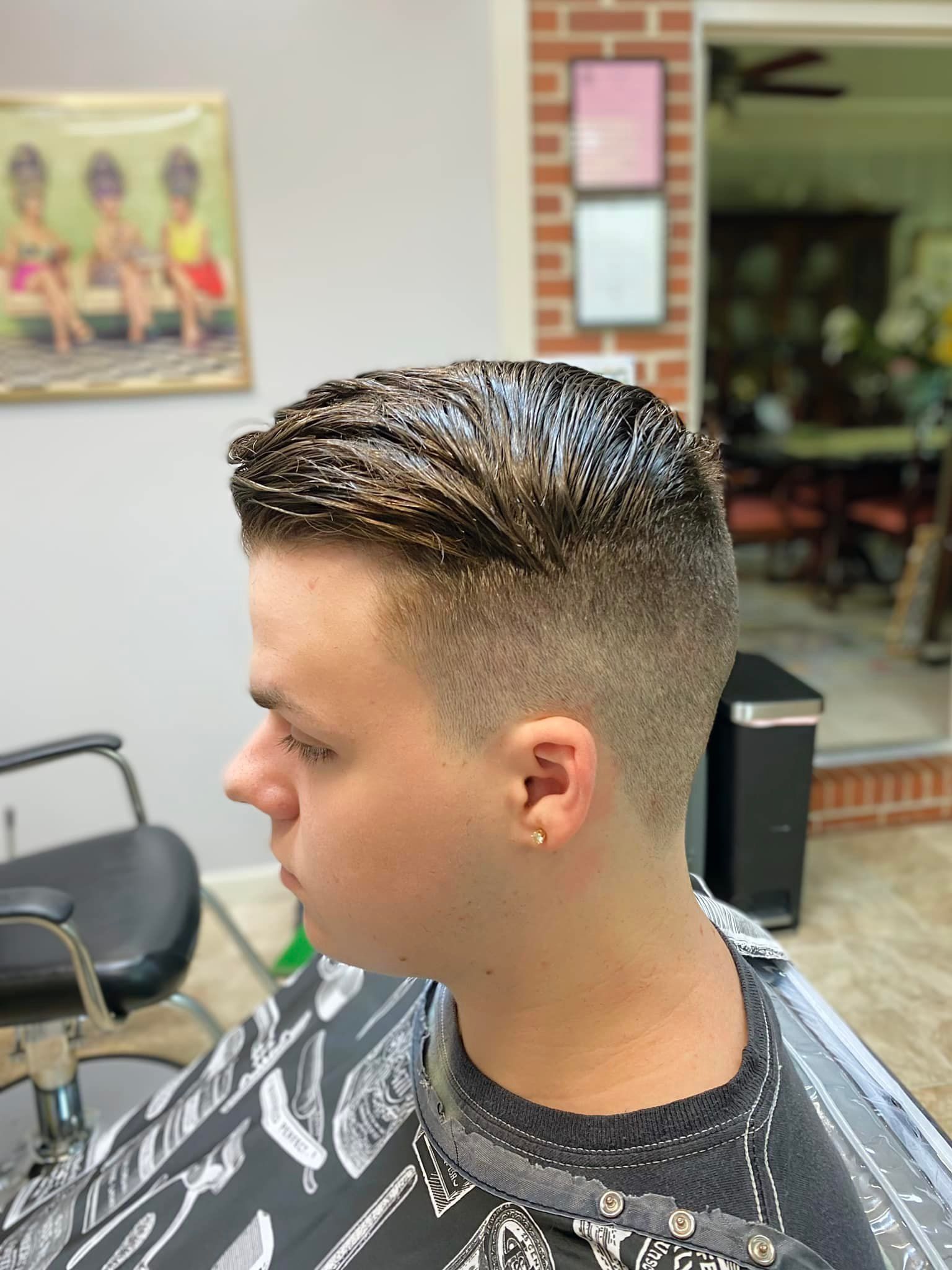 A young man is getting his hair cut at a barber shop.