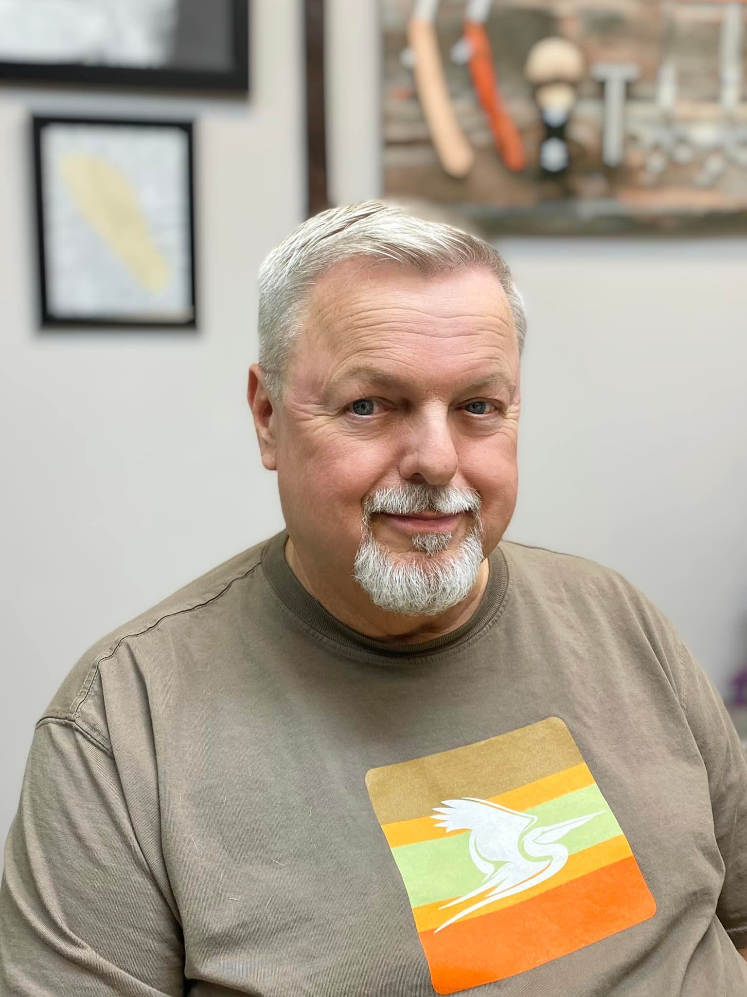 A man with a beard is wearing a t-shirt with a picture of a horse on it.