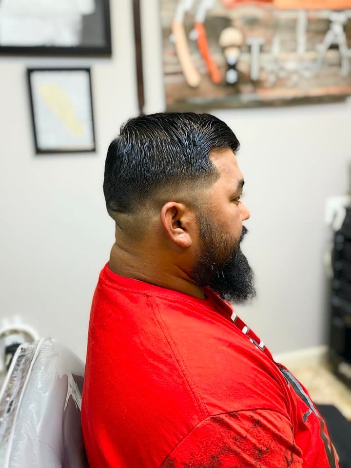 A man with a beard is getting his hair cut at a barber shop.