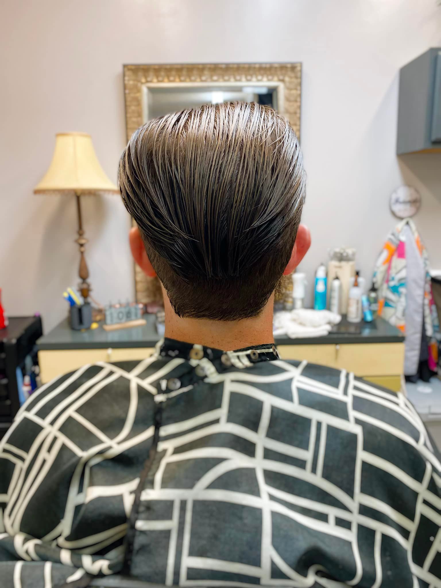 A man is getting his hair cut at a barber shop.