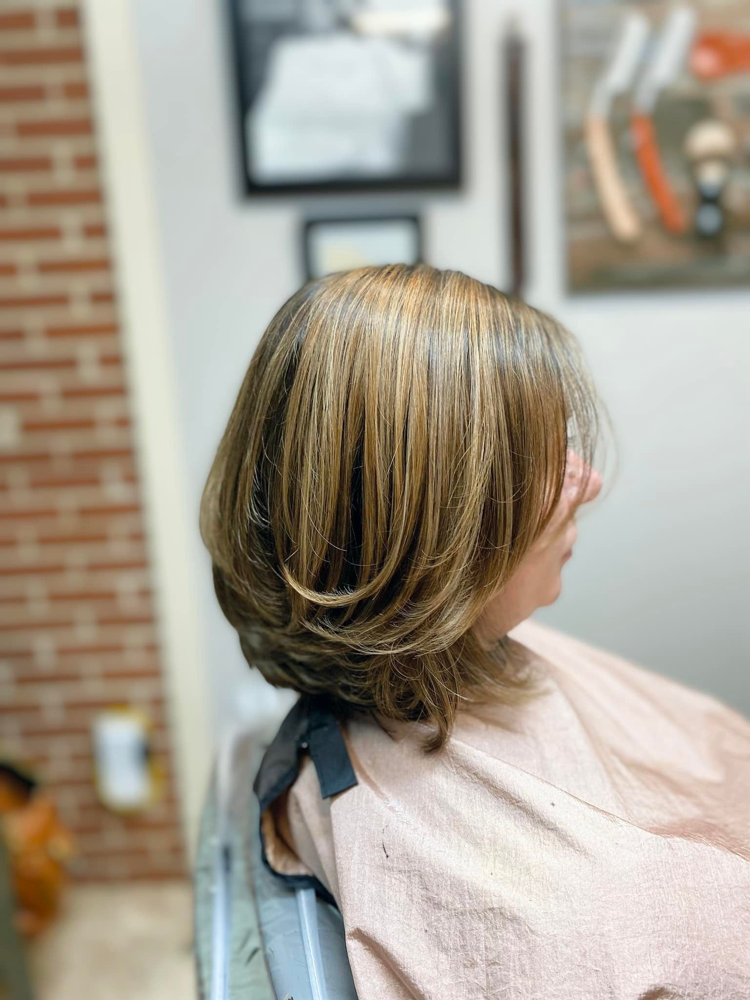 A woman is sitting in a chair with her hair covered in a towel.