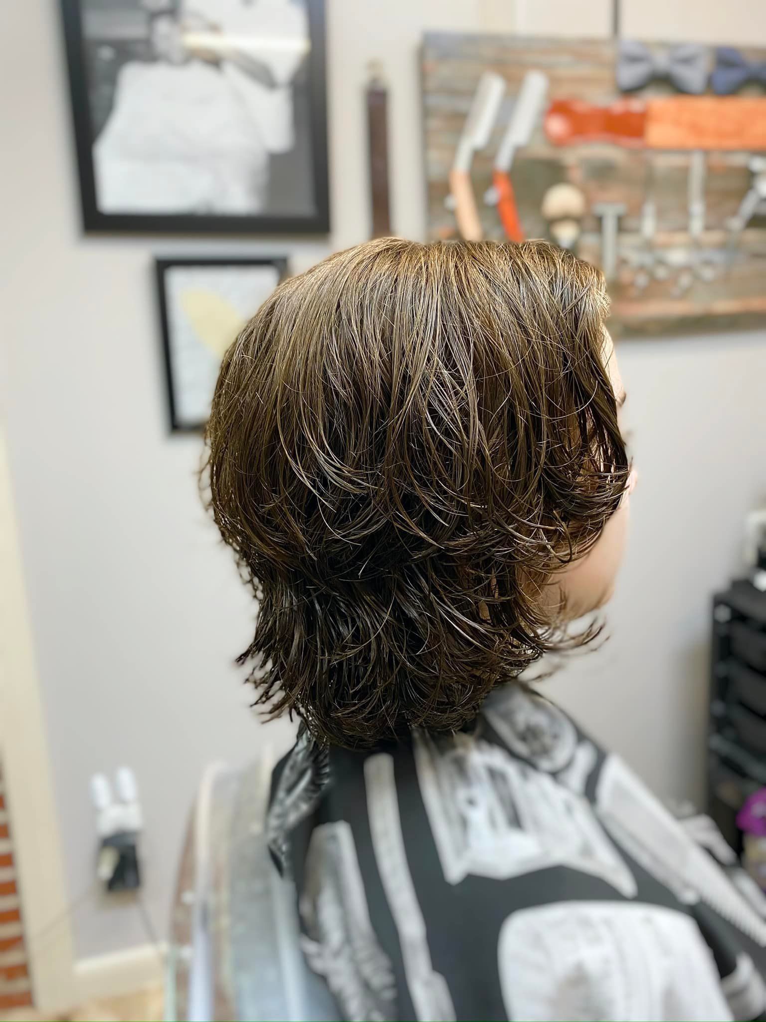 A woman is getting her hair cut at a barber shop.