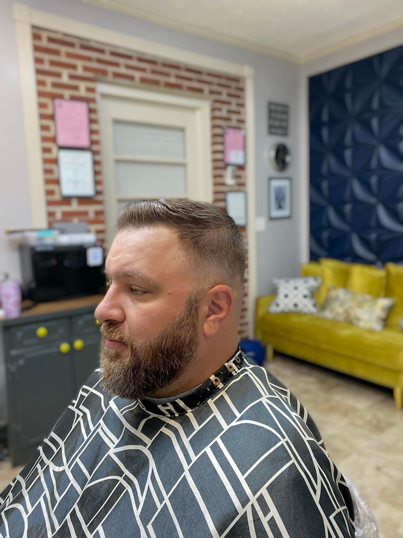 A man with a beard is getting his hair cut at a barber shop.