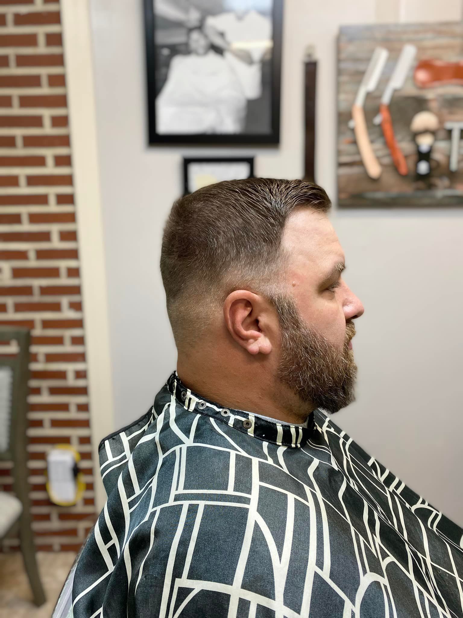A man with a beard is getting his hair cut at a barber shop.