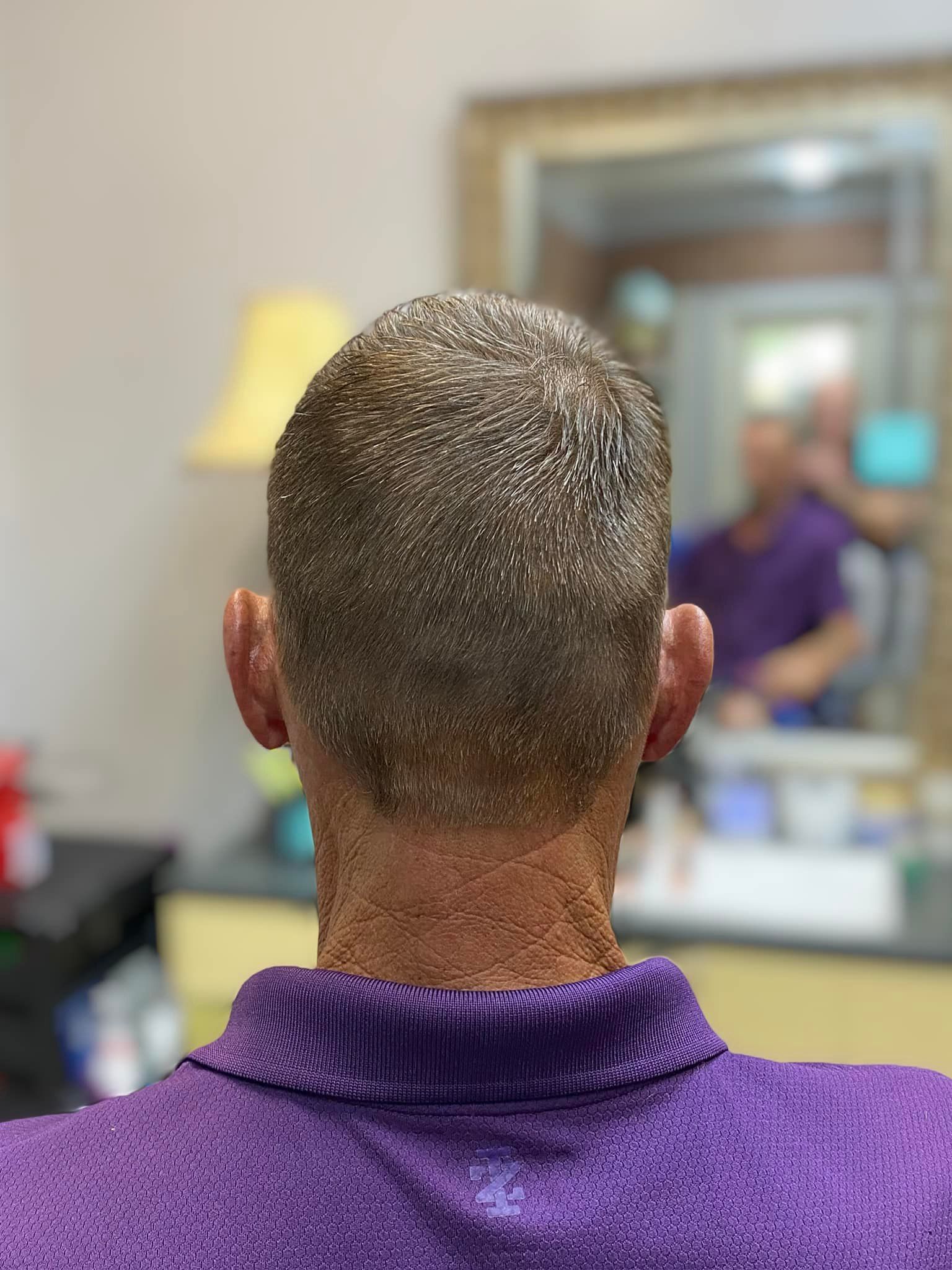 The back of a man 's head is shown in front of a mirror.