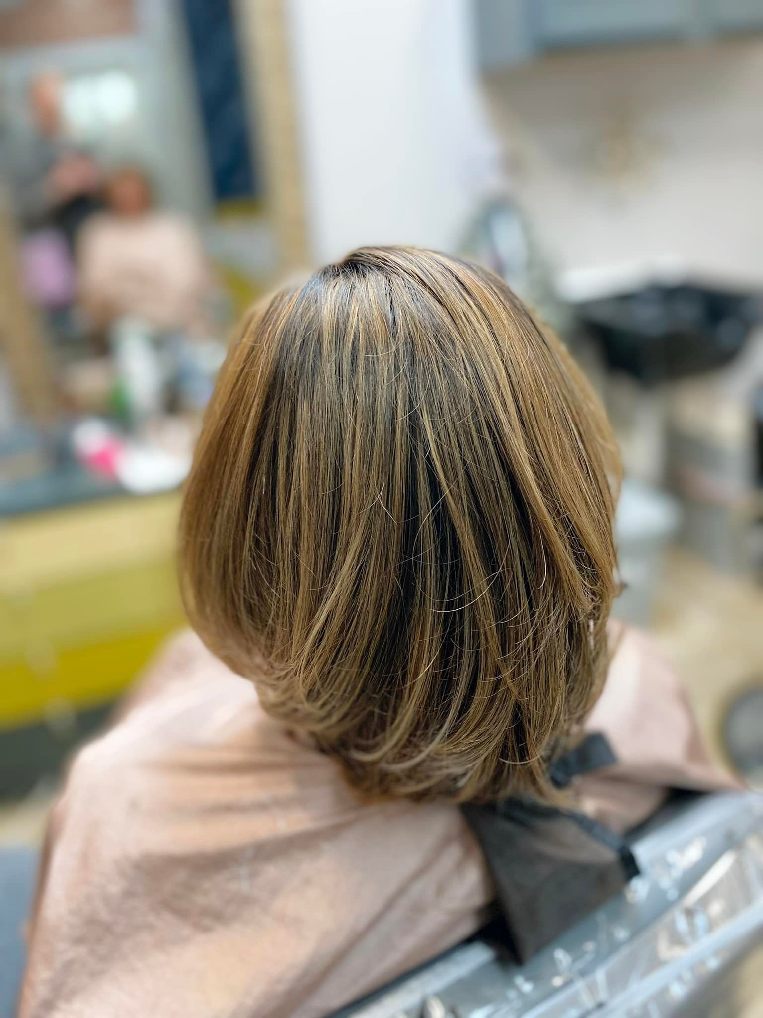 A woman is sitting in a chair with her hair dyed in a salon.