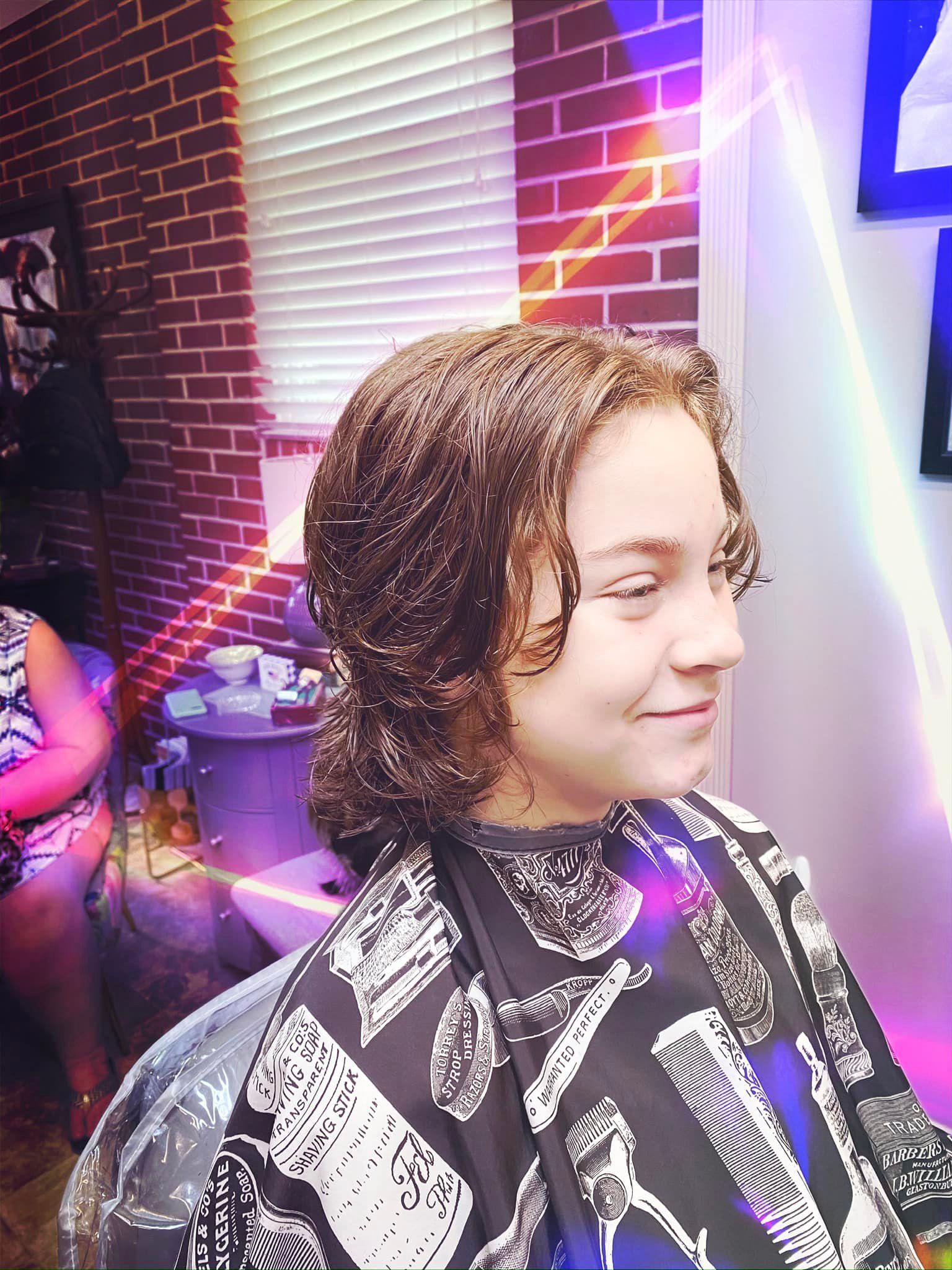 A young boy is getting his hair cut in a salon.
