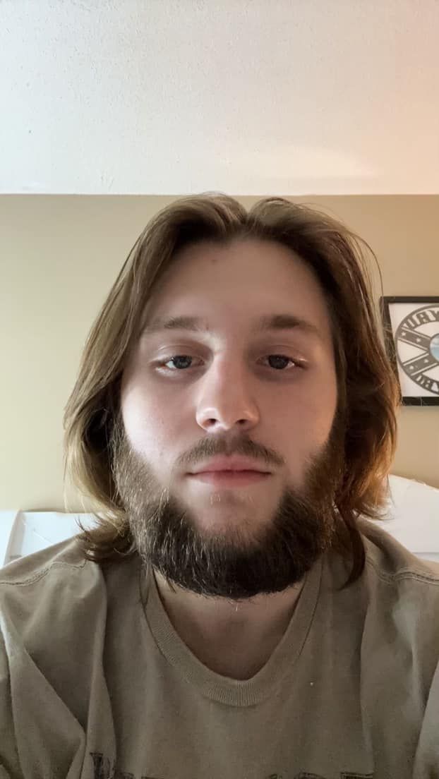 A man with long hair and a beard is looking at the camera.