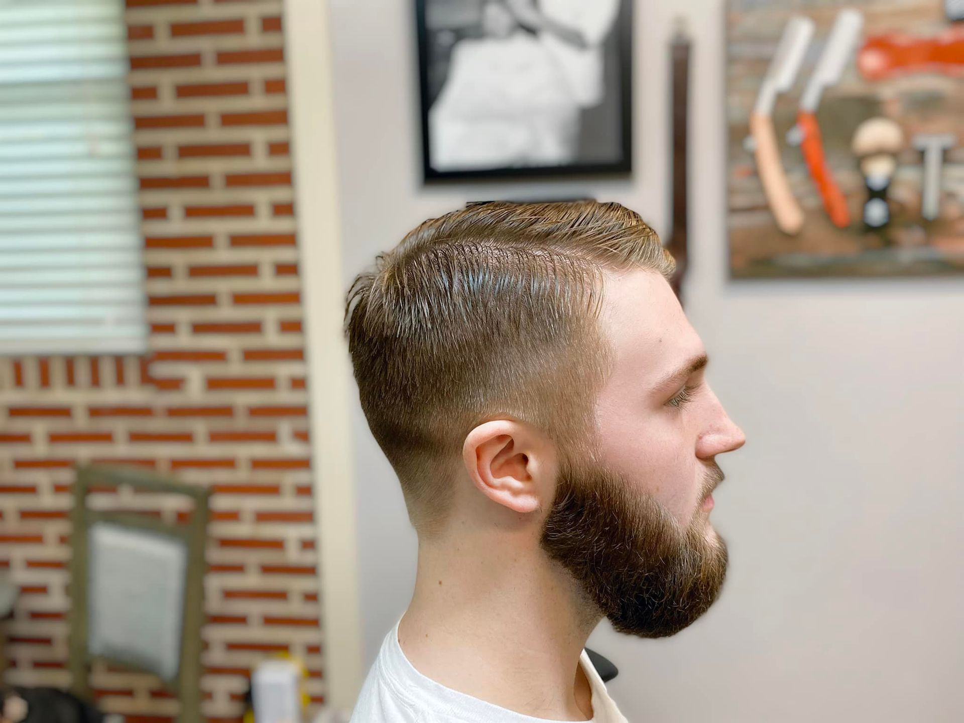 A man with a beard is getting his hair cut at a barber shop.