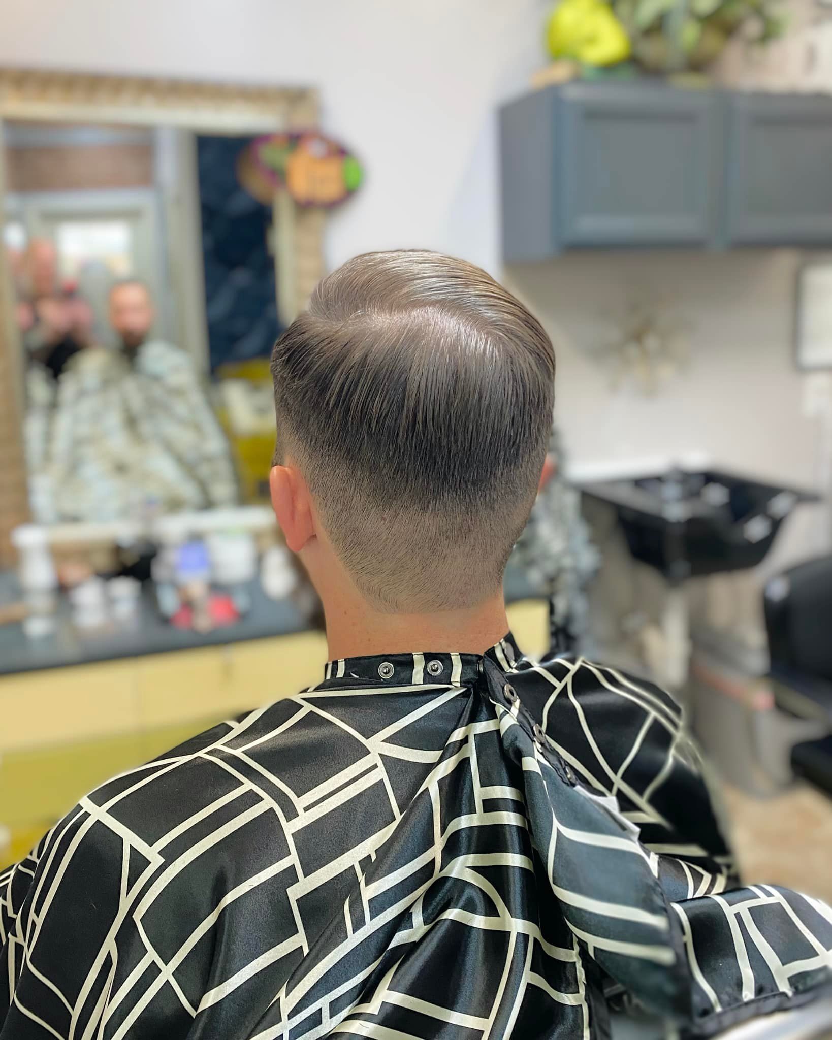 A man is getting his hair cut at a barber shop.