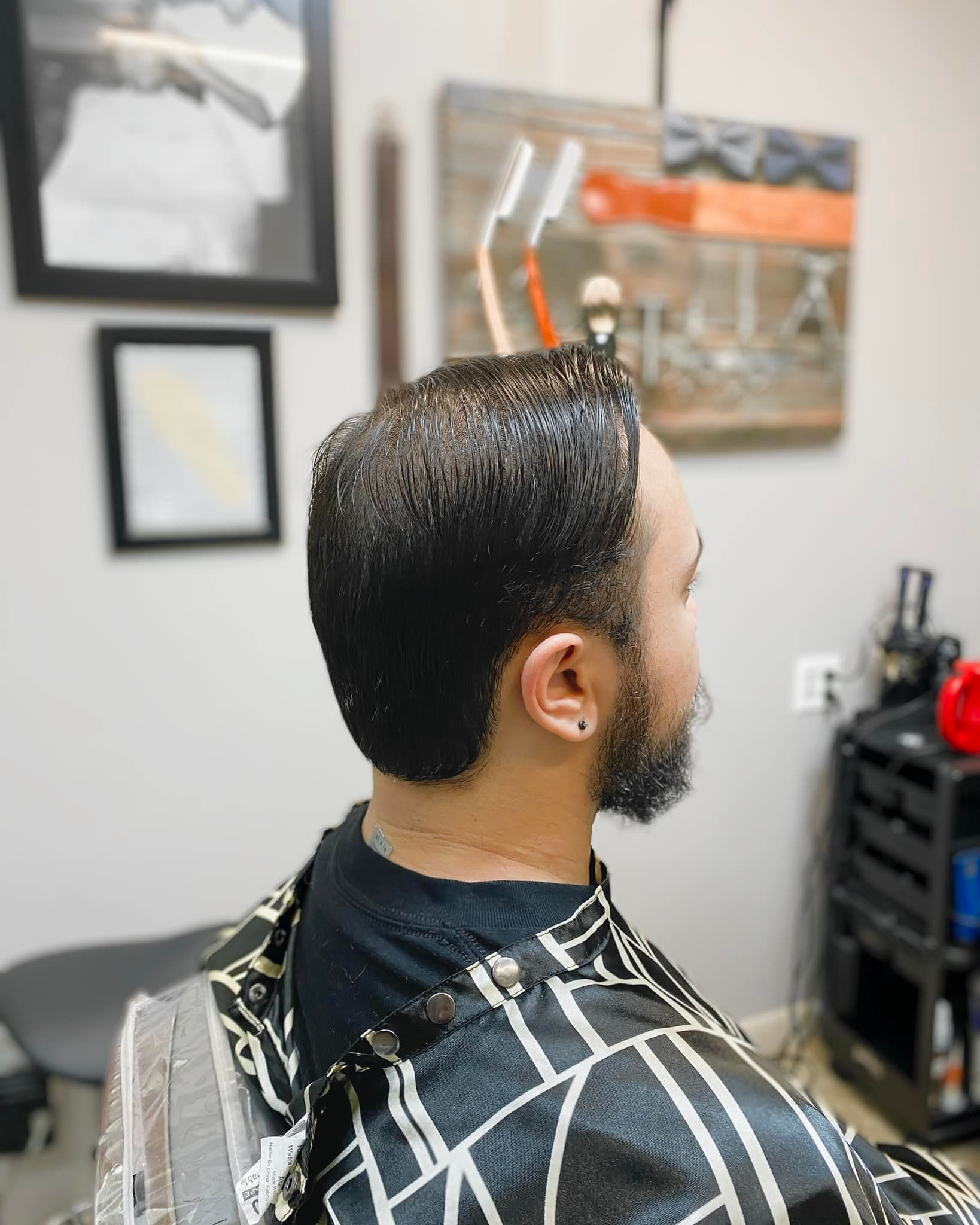 A man with a beard is getting his hair cut at a barber shop.