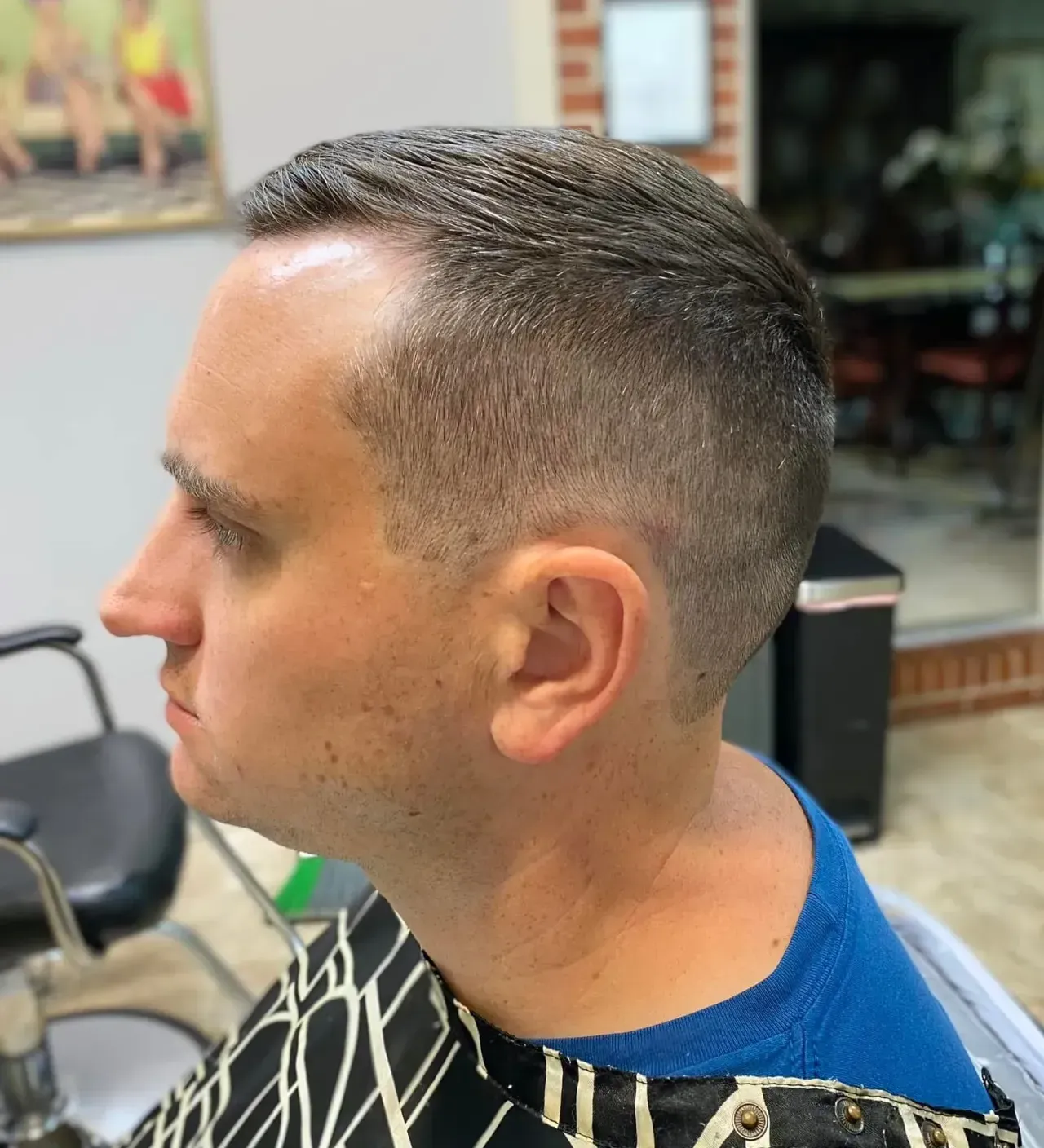 A man is getting his hair cut at a barber shop.