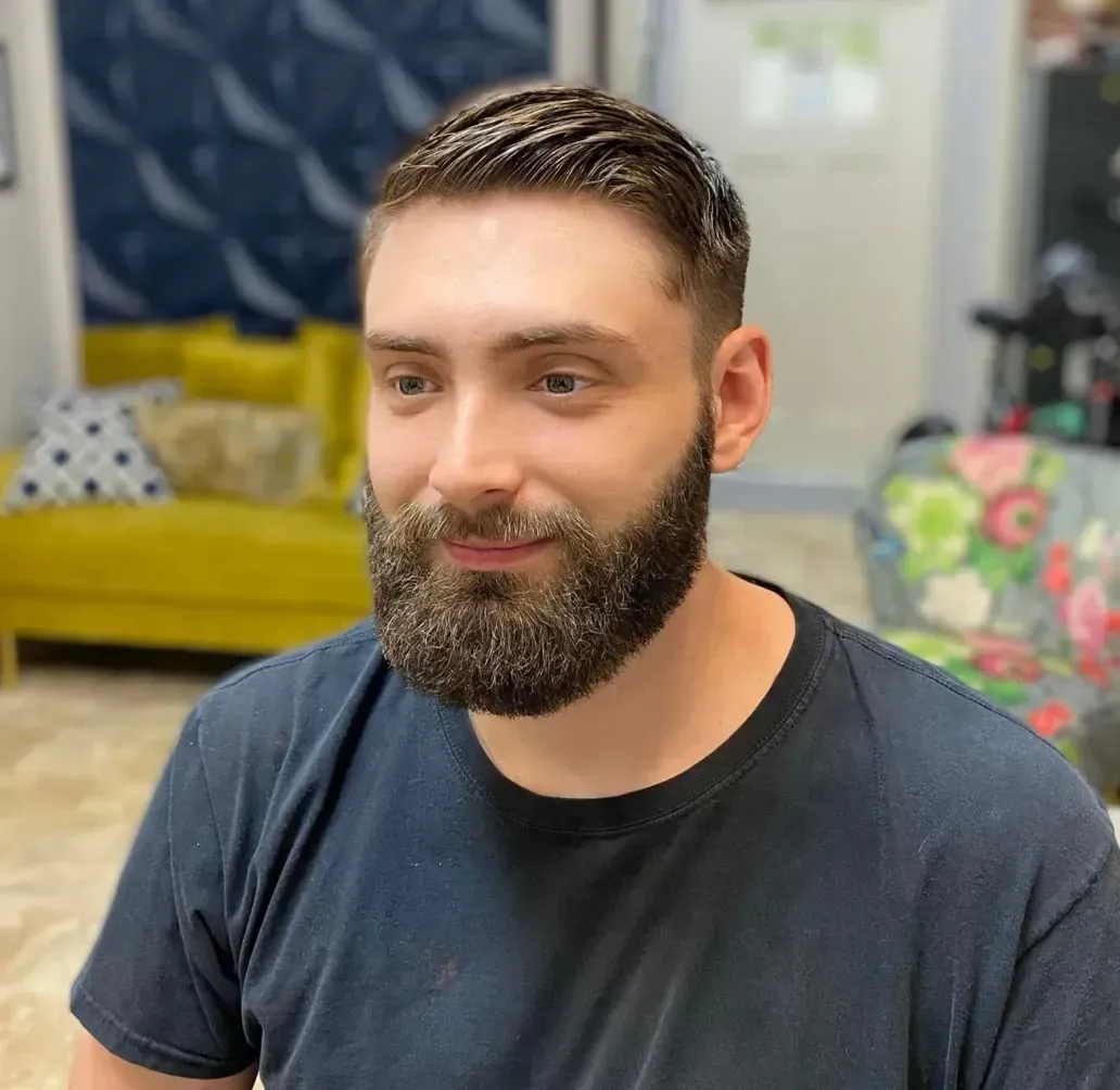 A man with a beard is wearing a black shirt and smiling.