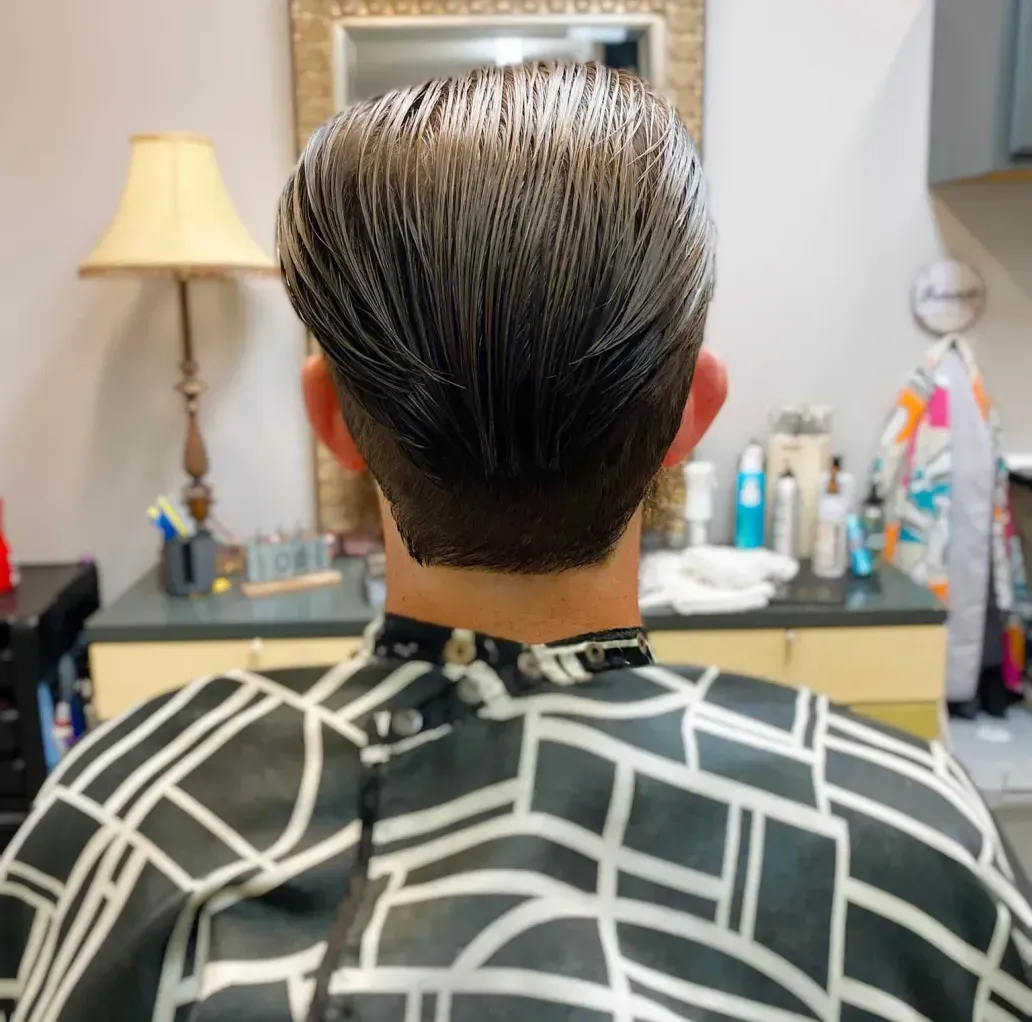 A man is getting his hair cut at a barber shop.