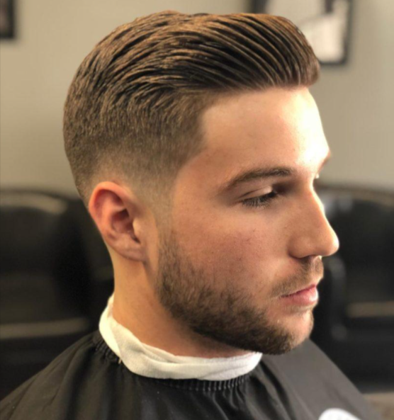 A man with a beard is getting his hair cut at a barber shop