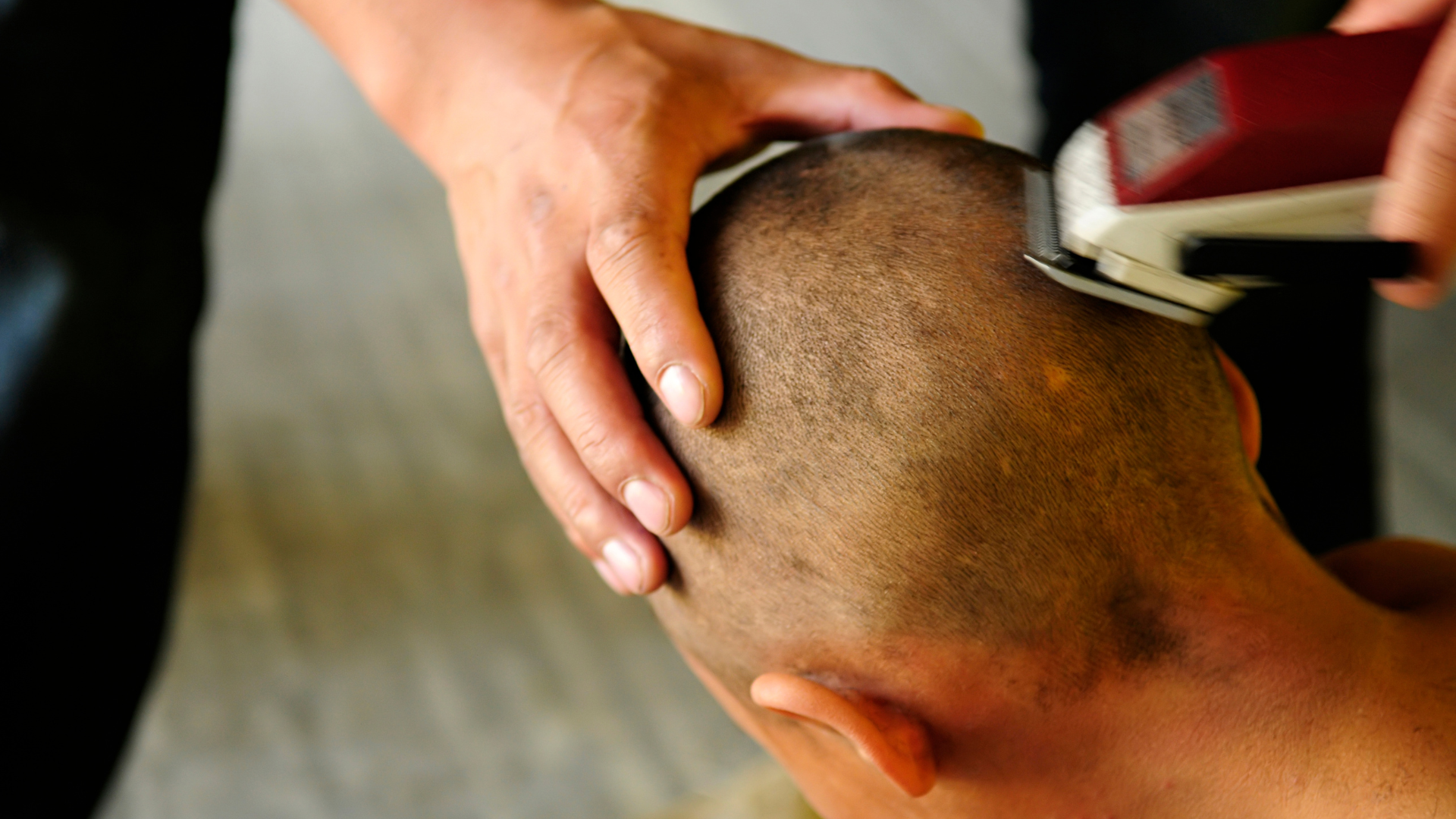 A man is getting his head shaved with a clipper.
