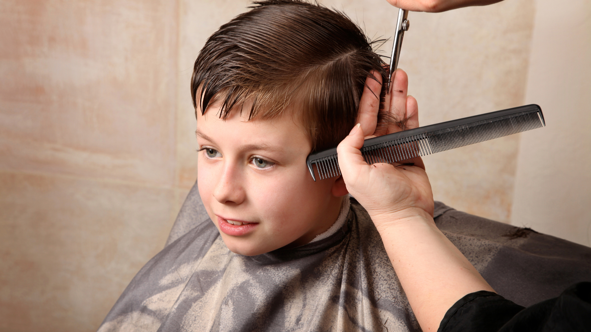 A young boy is getting his hair cut by a barber.