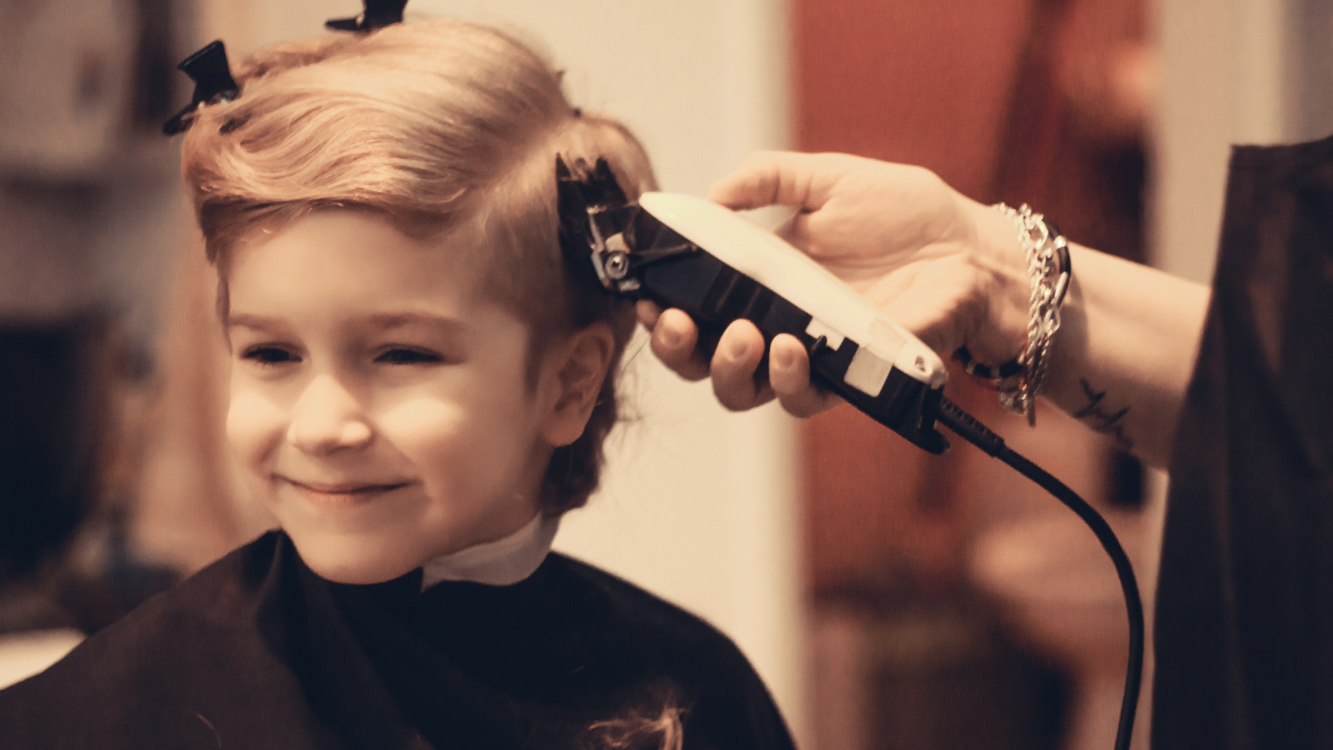 A little boy is getting his hair cut by a woman.