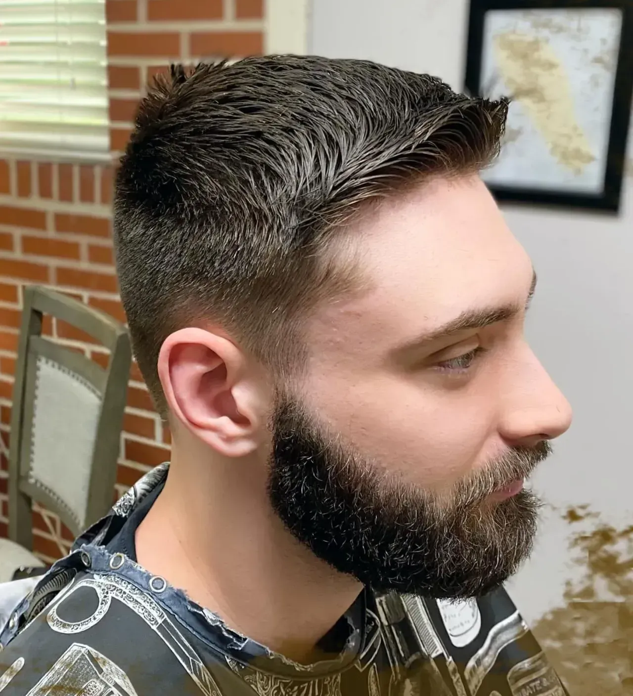 A man with a beard is getting his hair cut at a barber shop